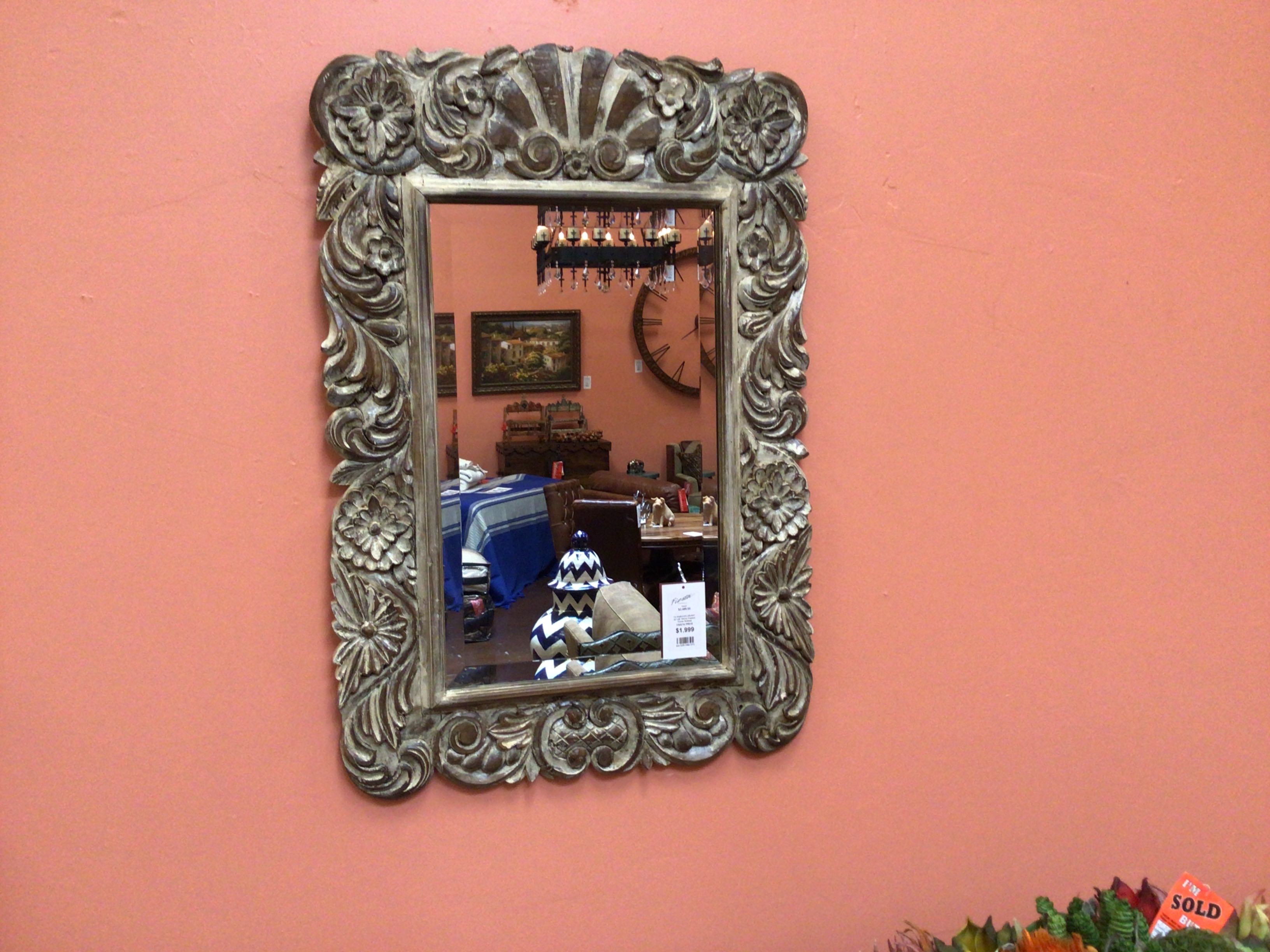 Decorative mirror with intricate frame on a pink wall