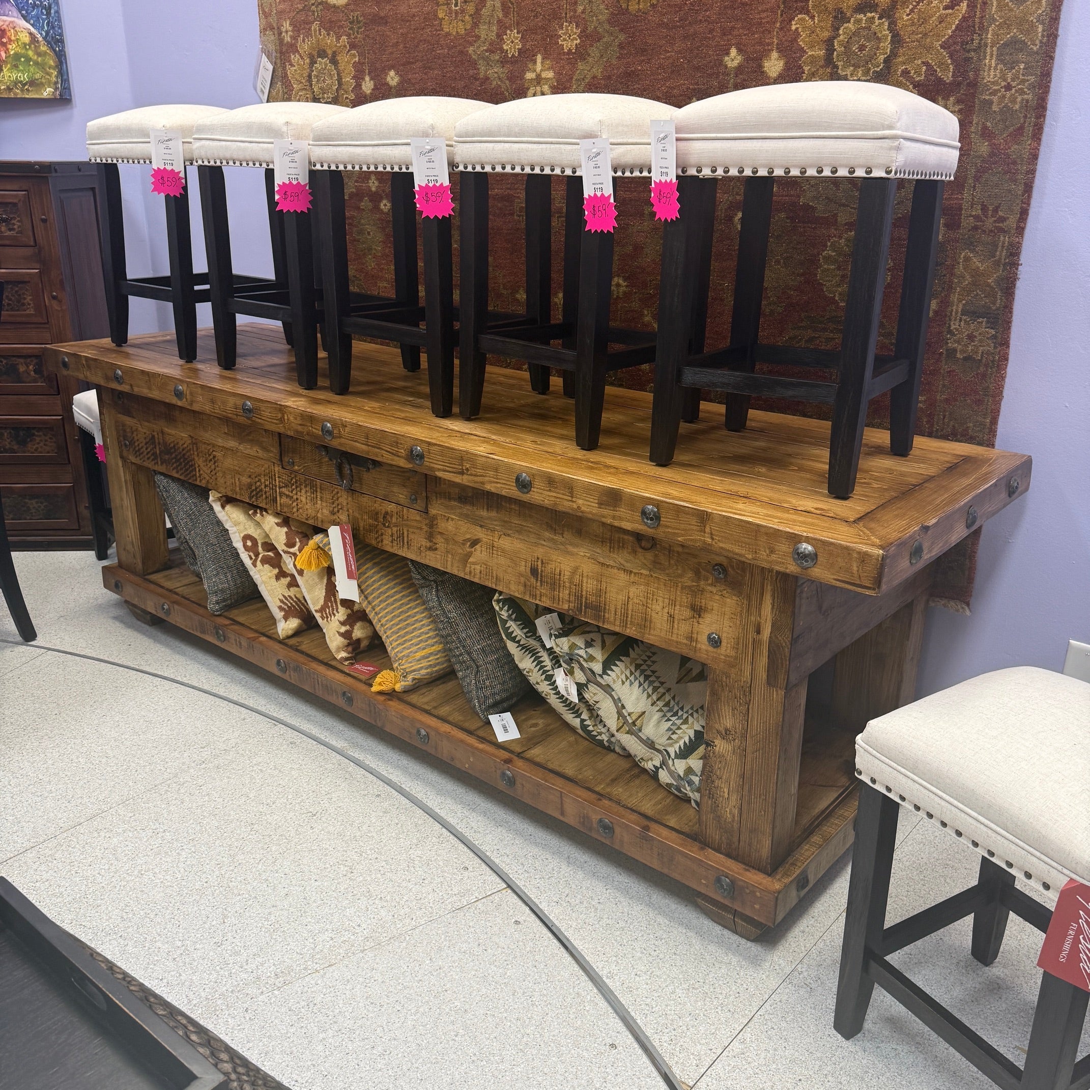 Wooden console table with upholstered stools in a store setting