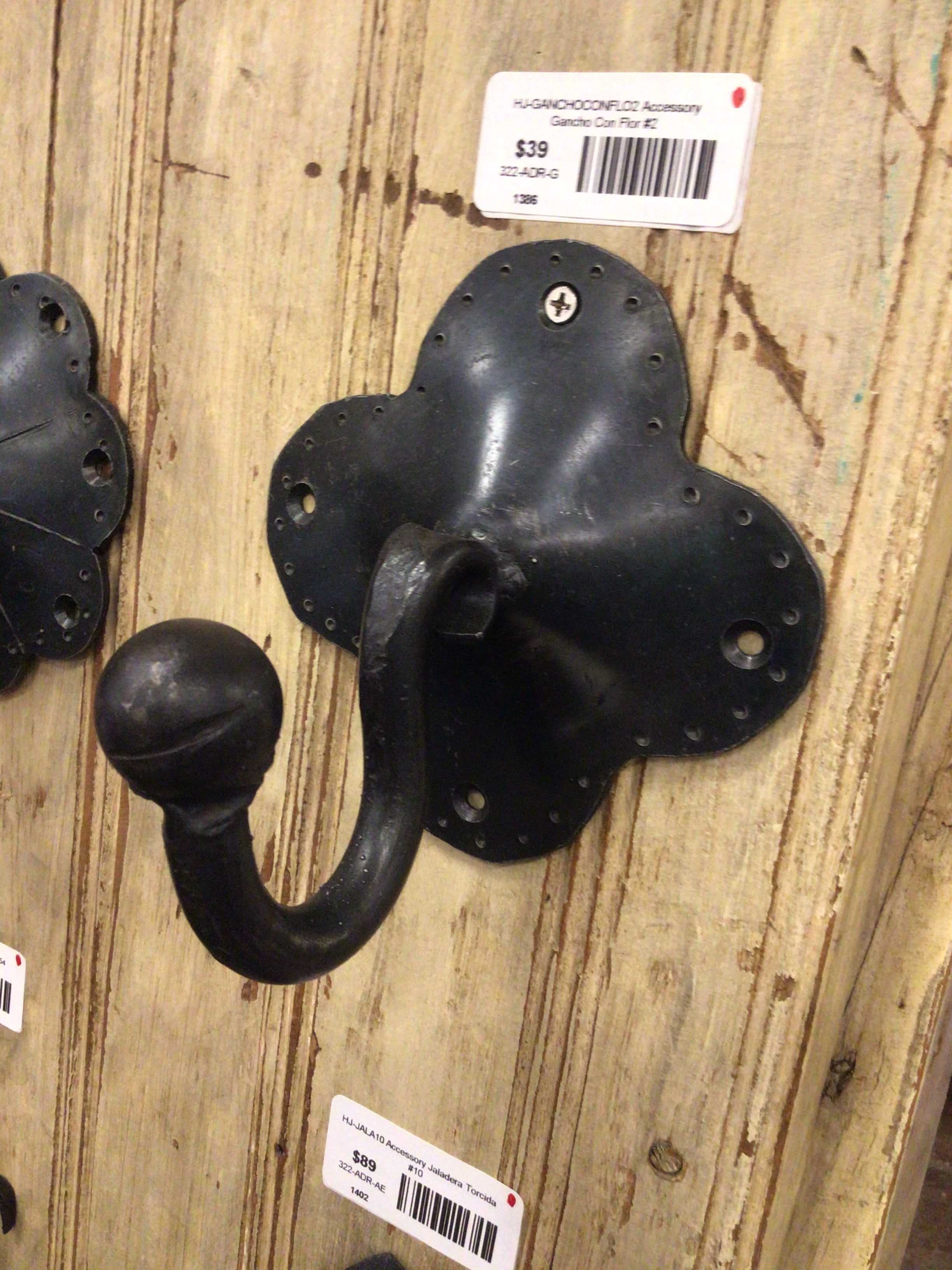 Black metal wall hook on a wooden surface with a price tag.