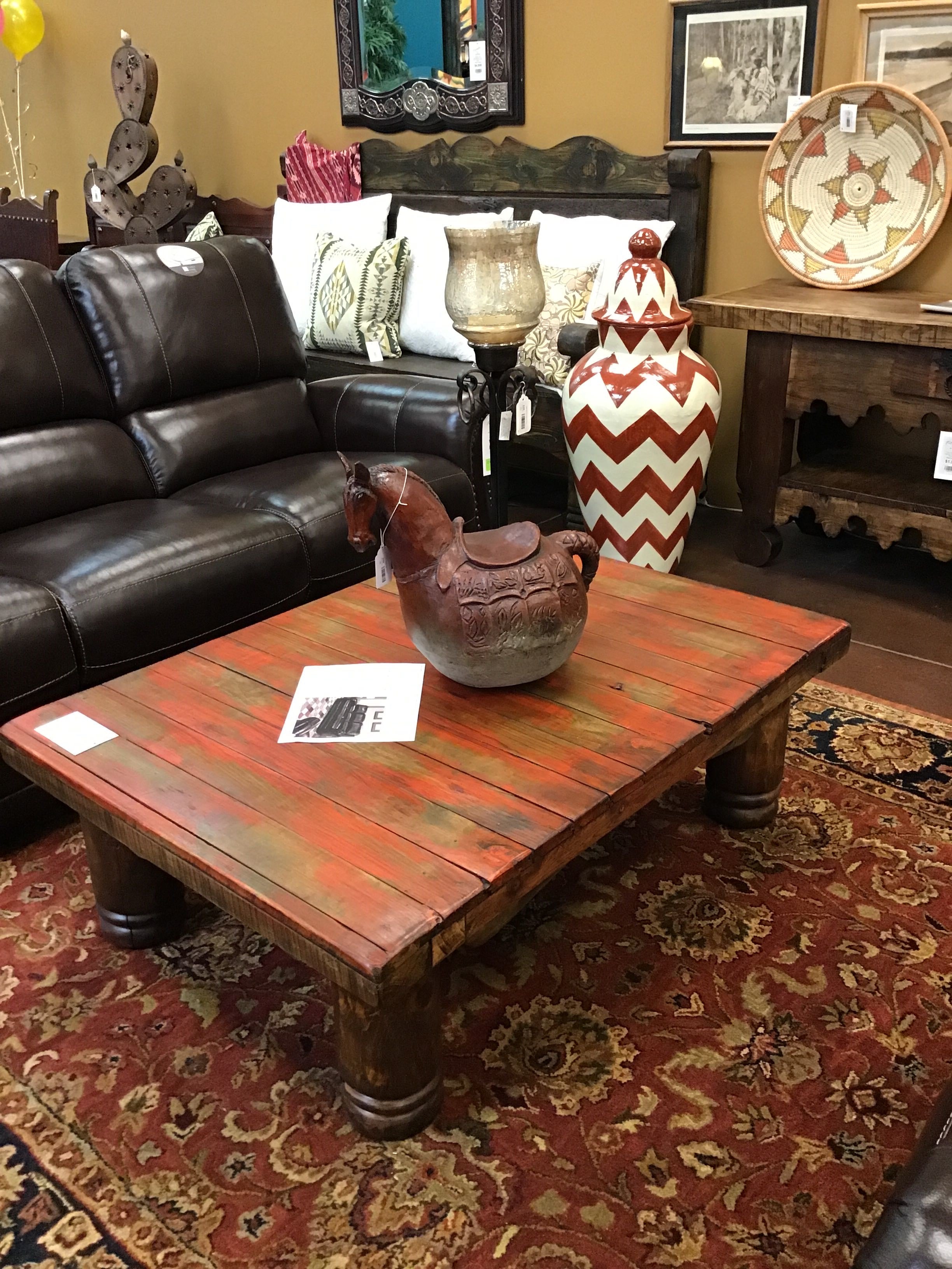 Living room with a brown leather sofa, wooden coffee table, and decorative items.