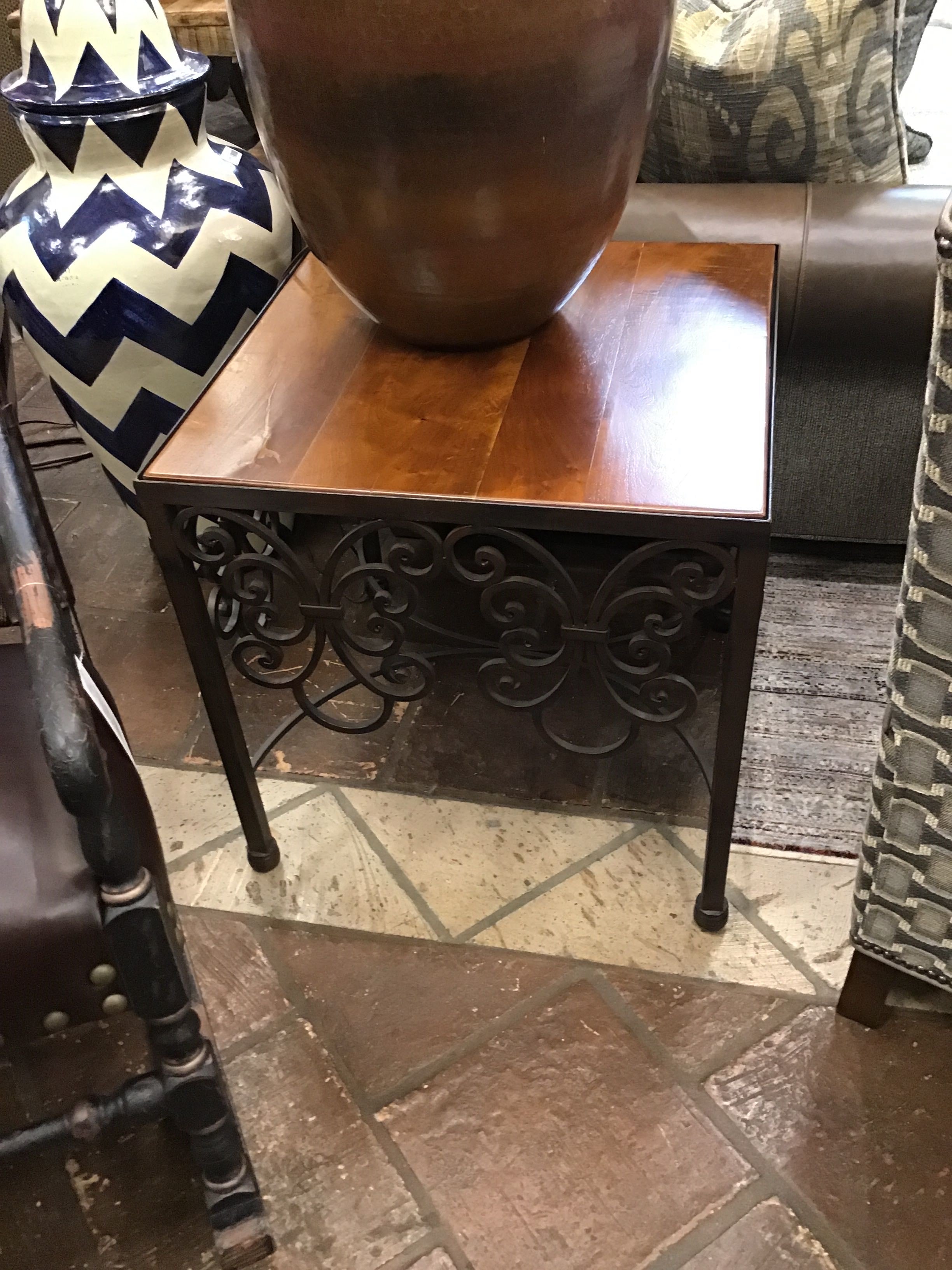 Small wooden table with decorative metal stand on a tiled floor