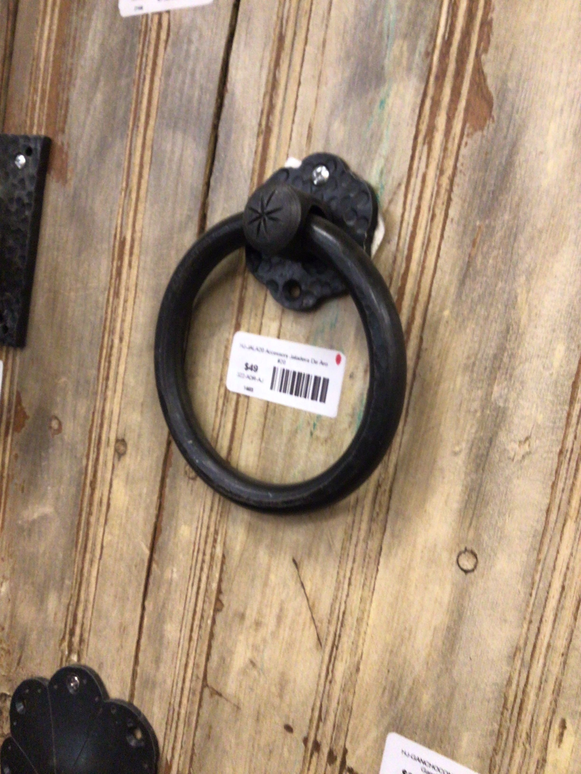 Black metal ring handle on a wooden surface with a barcode label.