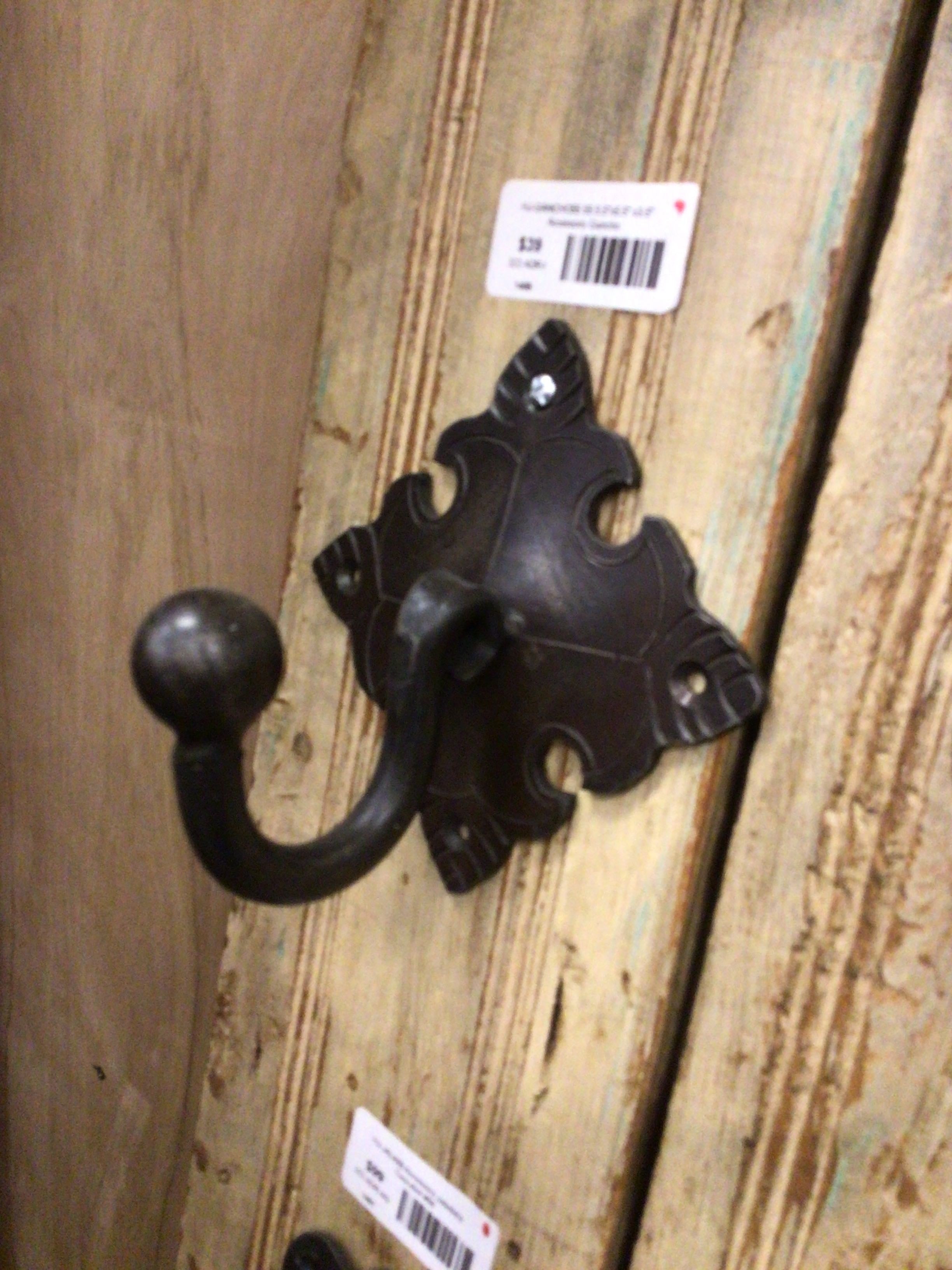 Decorative black wall hook on a wooden surface with a visible barcode label.