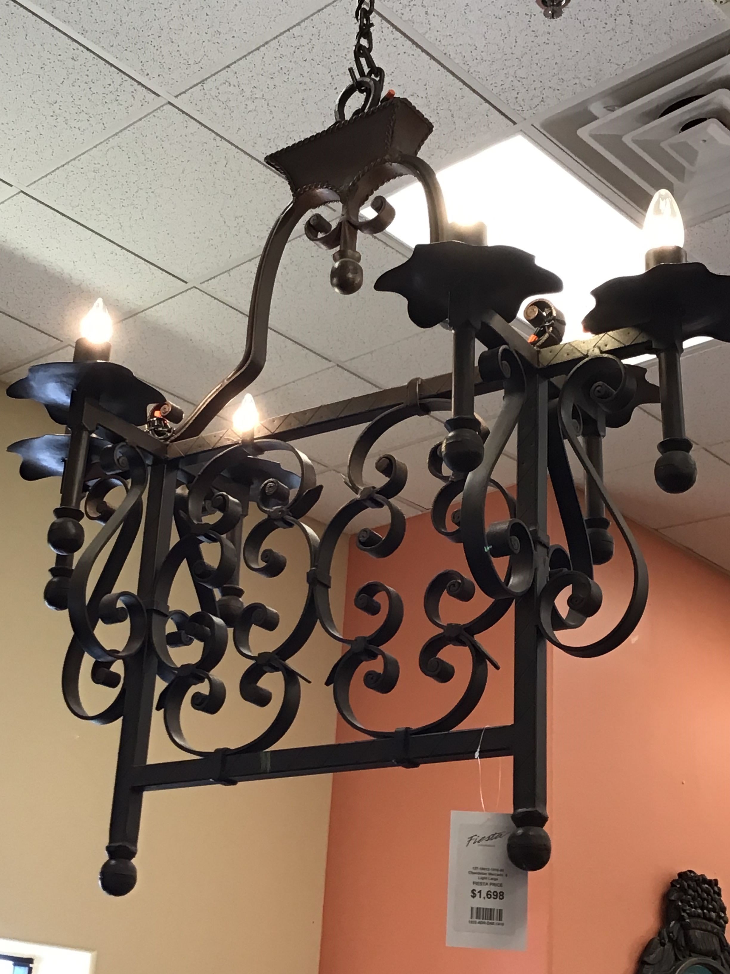 Decorative black wrought iron chandelier with lights on a ceiling.