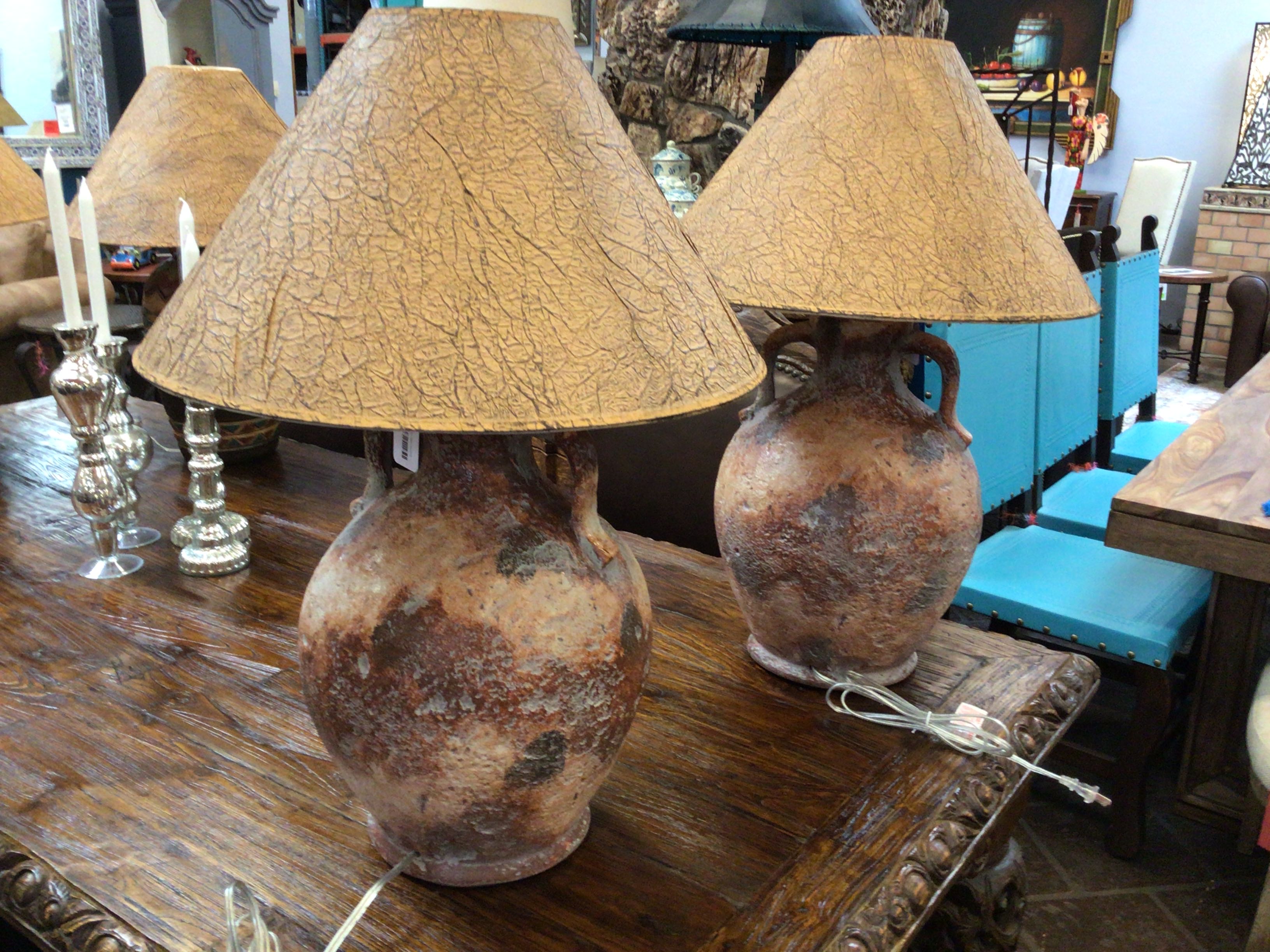 Two rustic ceramic lamps with cracked beige lampshades on a wooden table.