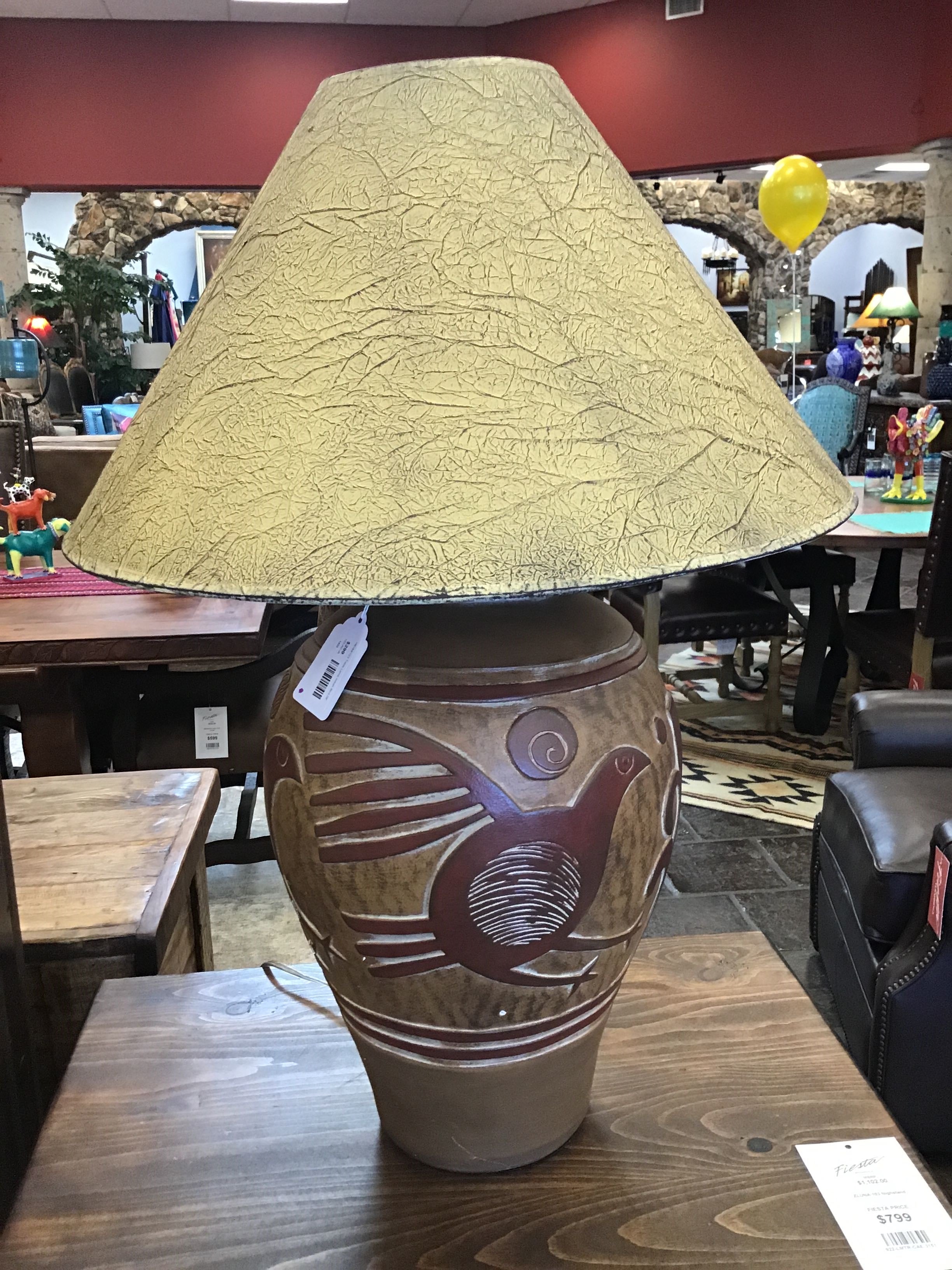 Decorative lamp with a textured shade on a wooden table in a store setting.