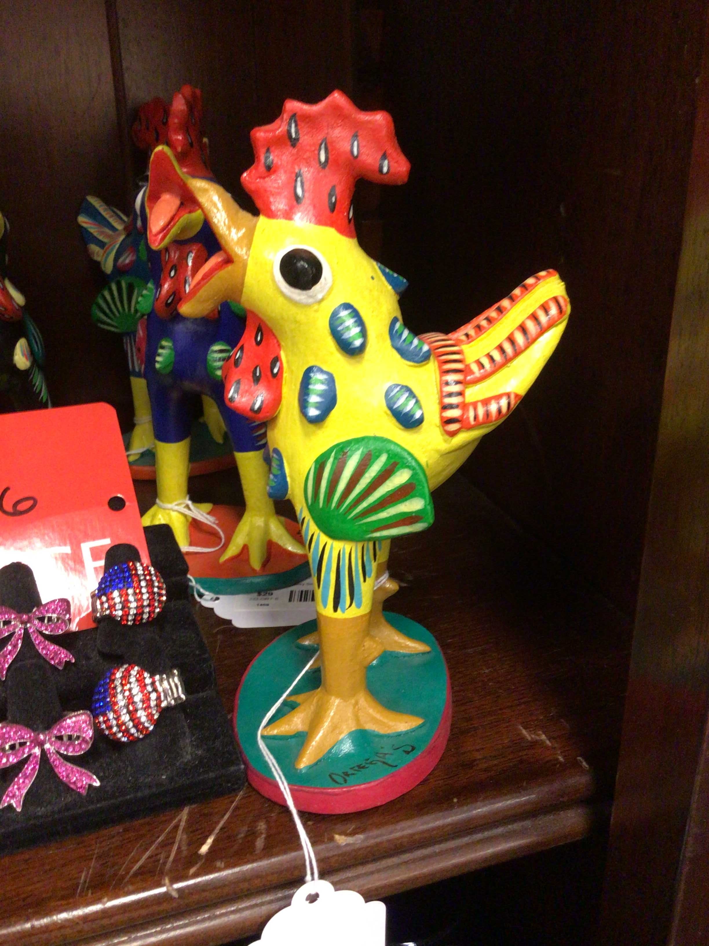 Colorful ceramic rooster figurine on a wooden surface with other decorative items.