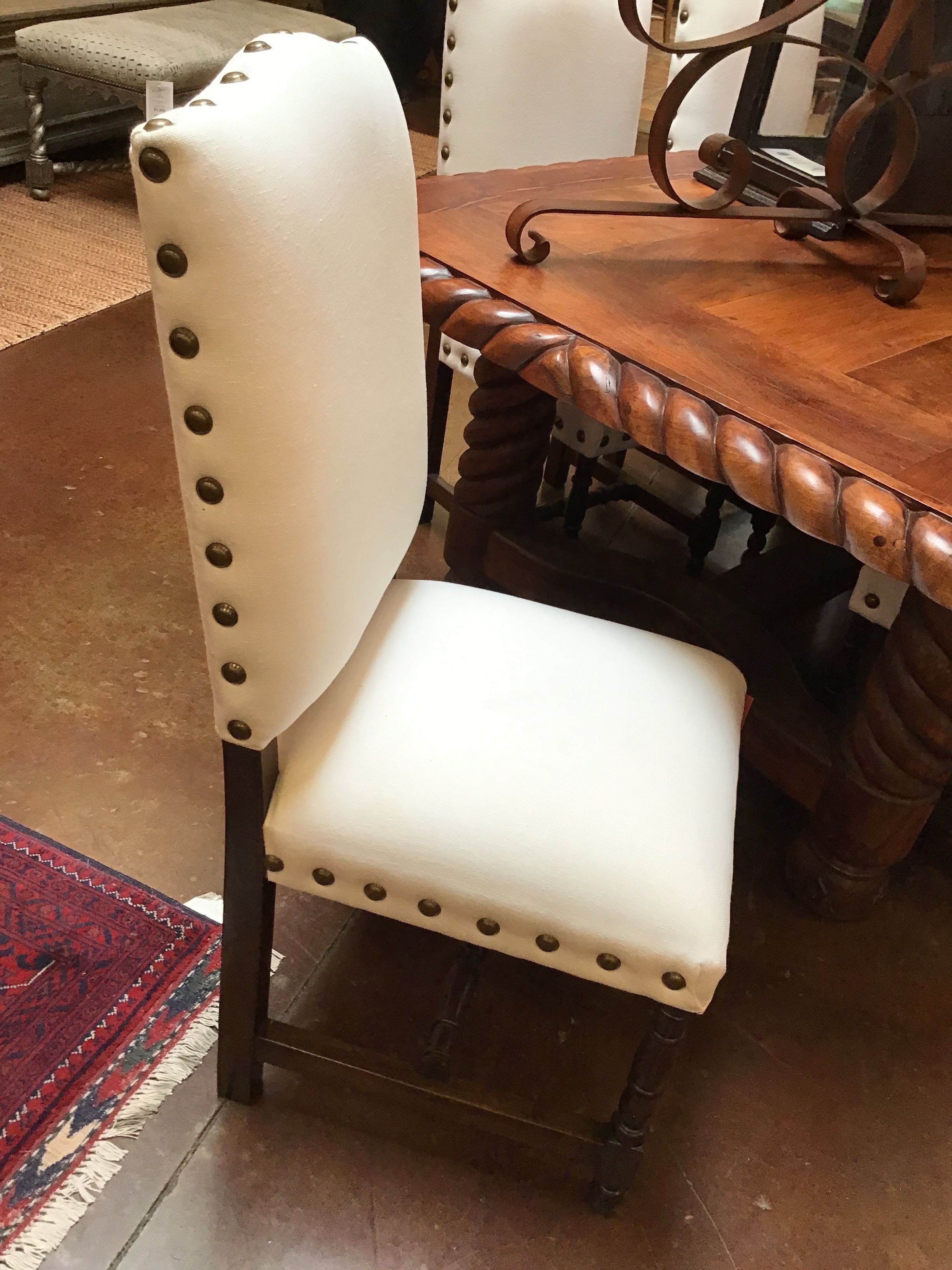 White chair with decorative buttons in a room with wooden furniture and a rug.