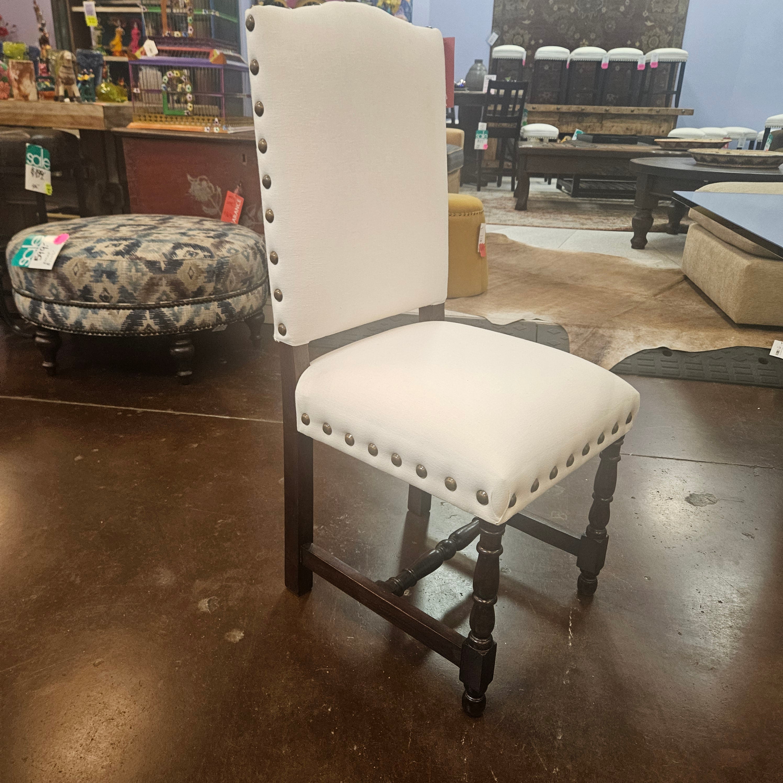 White folding chair with black metal legs on a concrete floor.