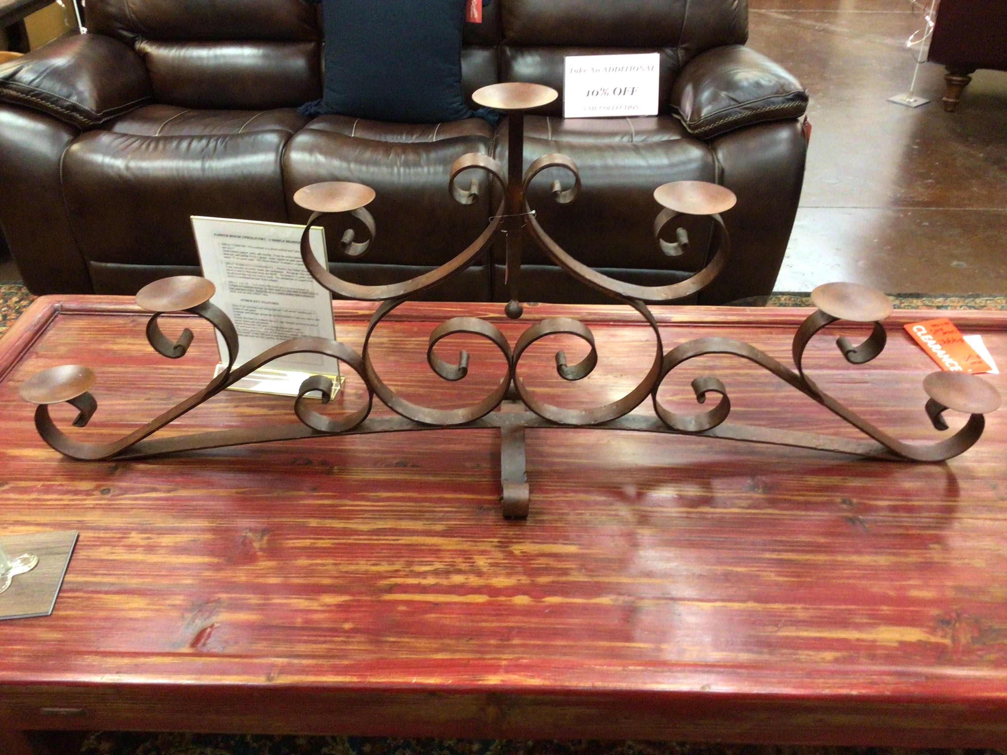 Decorative metal candle holder on a wooden table with a brown leather sofa in the background.
