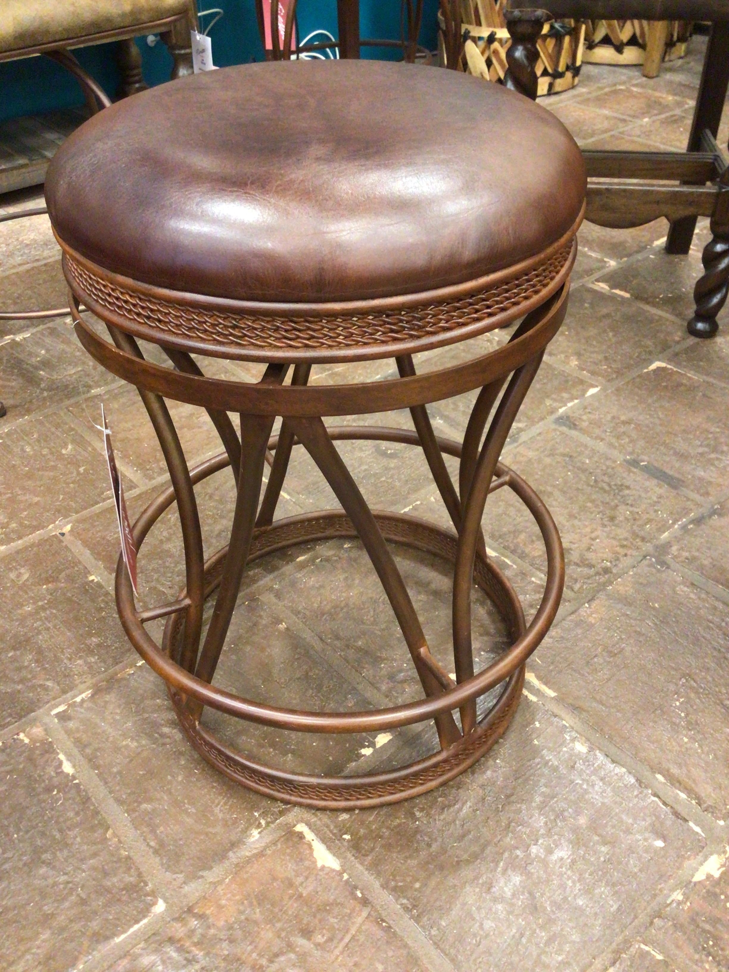 Brown leather stool with metal frame on a stone floor