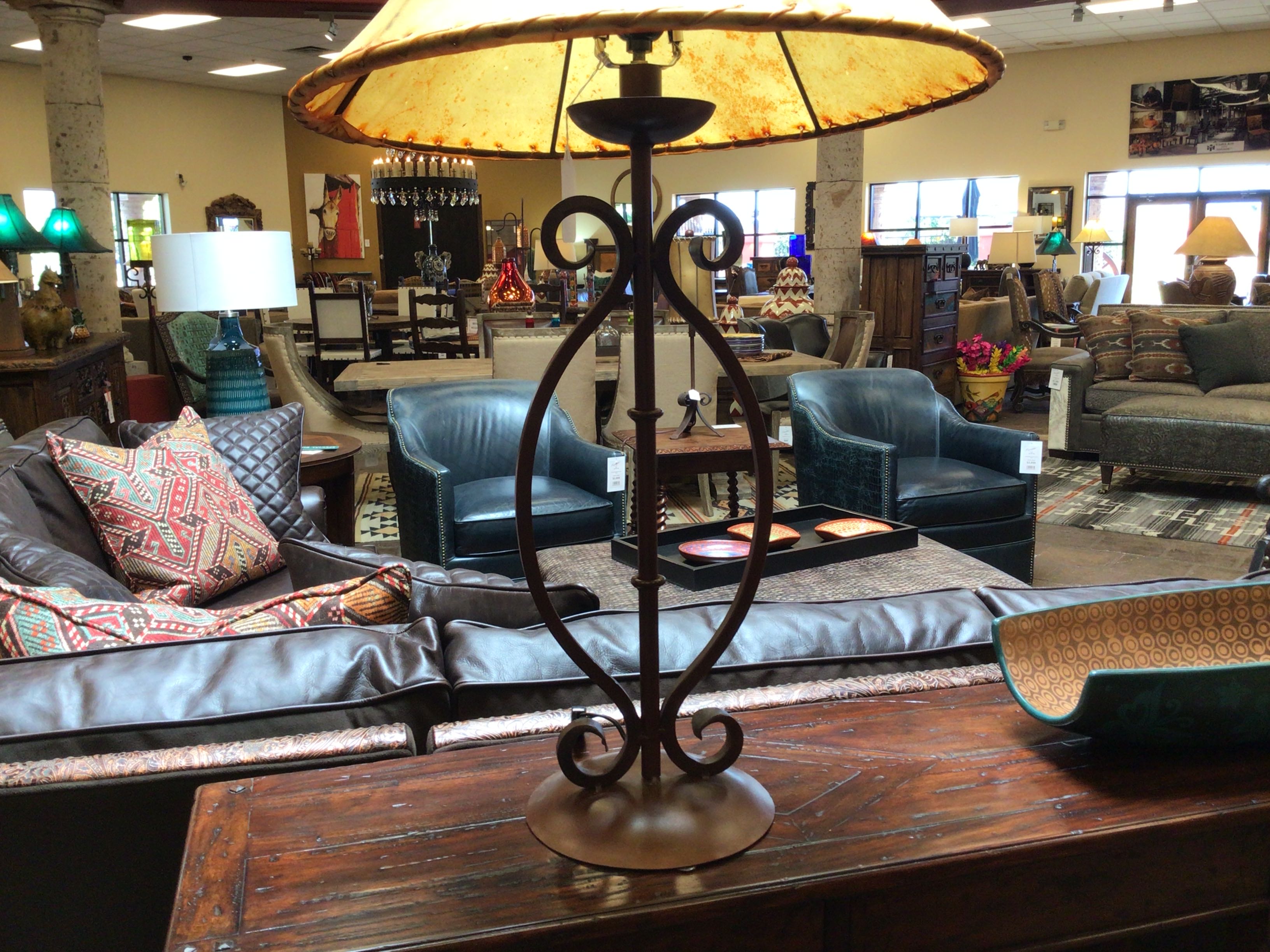 Decorative lamp on a wooden table in a furniture store with sofas and chairs in the background.