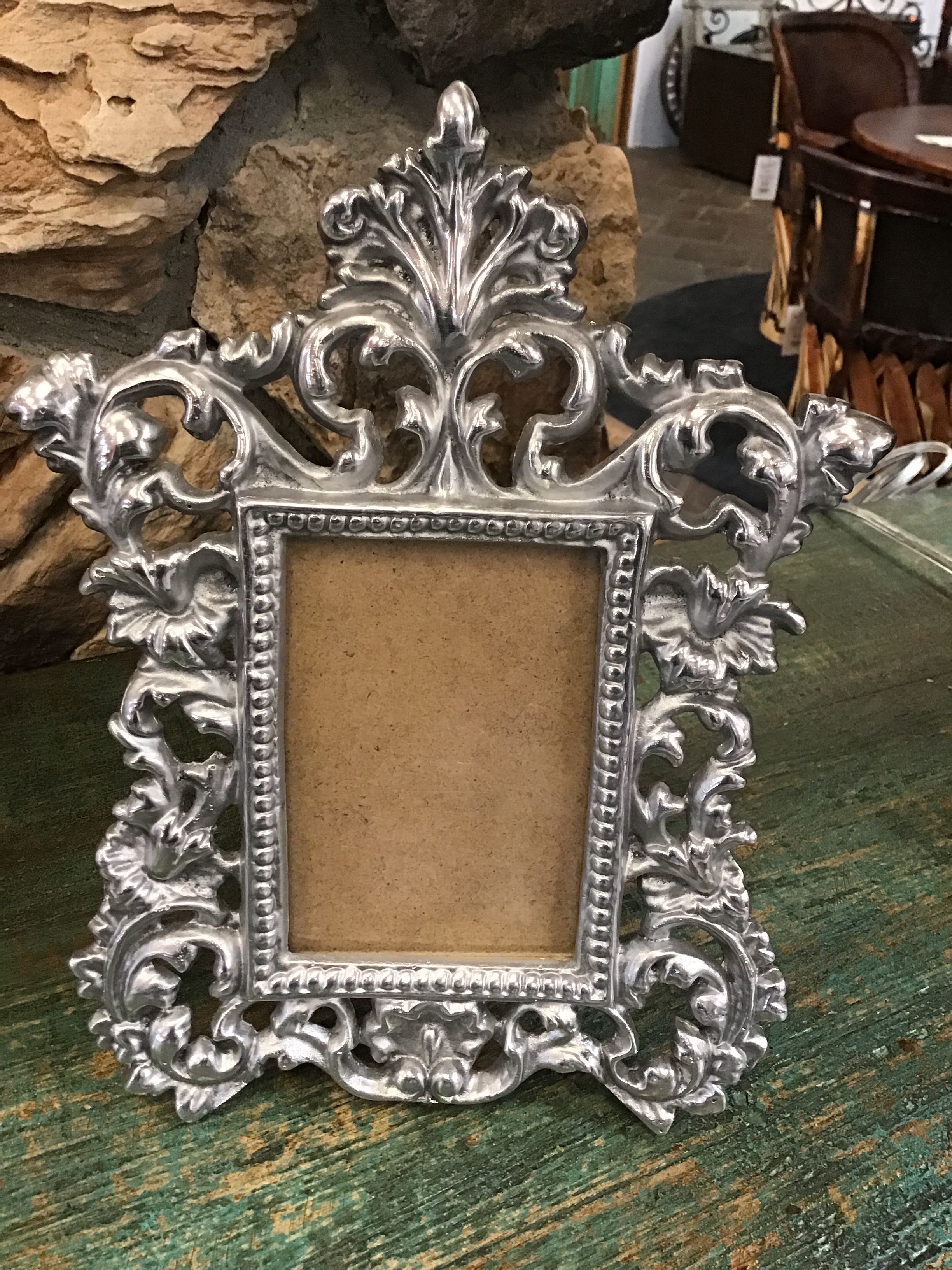 Decorative silver picture frame on a wooden surface with a stone wall background