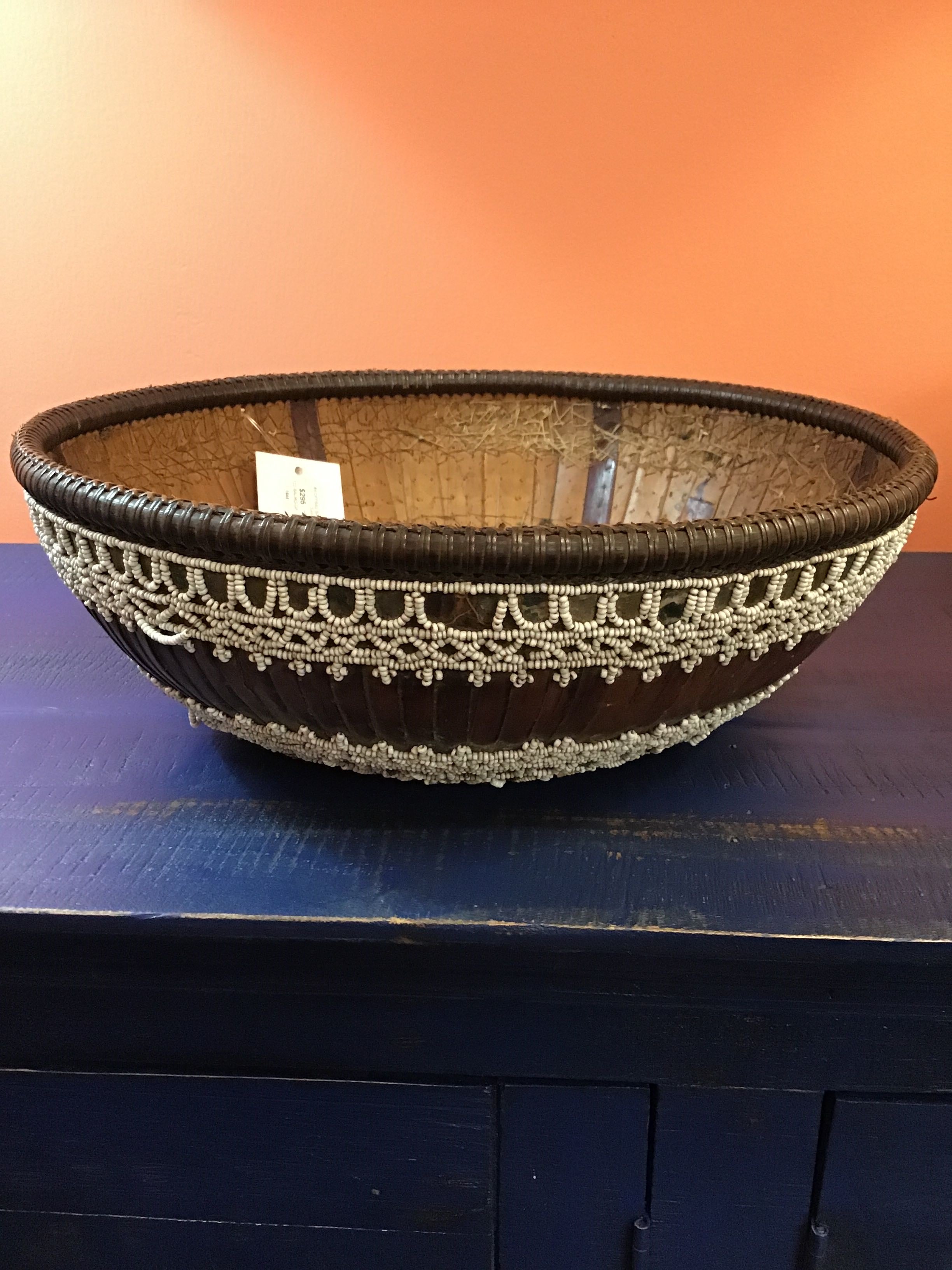 Woven basket with decorative elements on a blue surface against an orange background