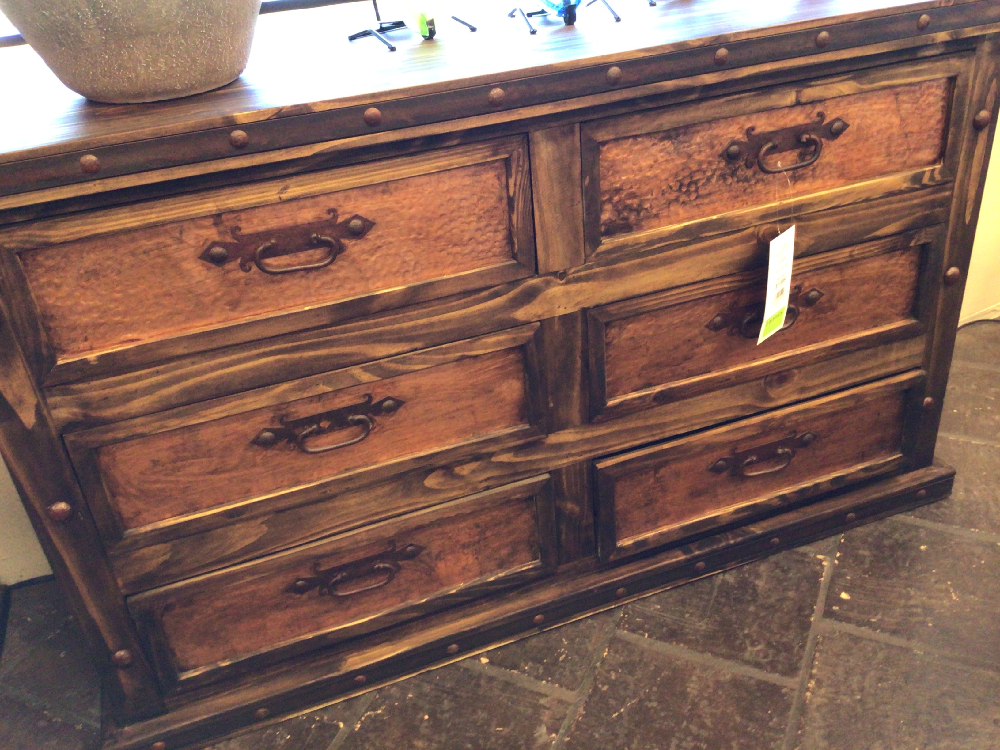 Wooden dresser with multiple drawers on a stone floor