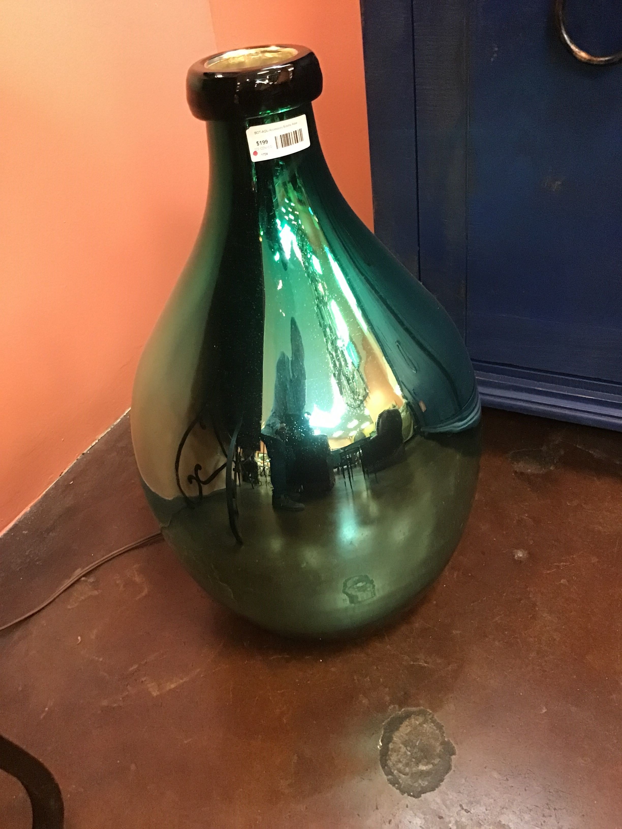 Green glass bottle on a reflective surface with a blurred background