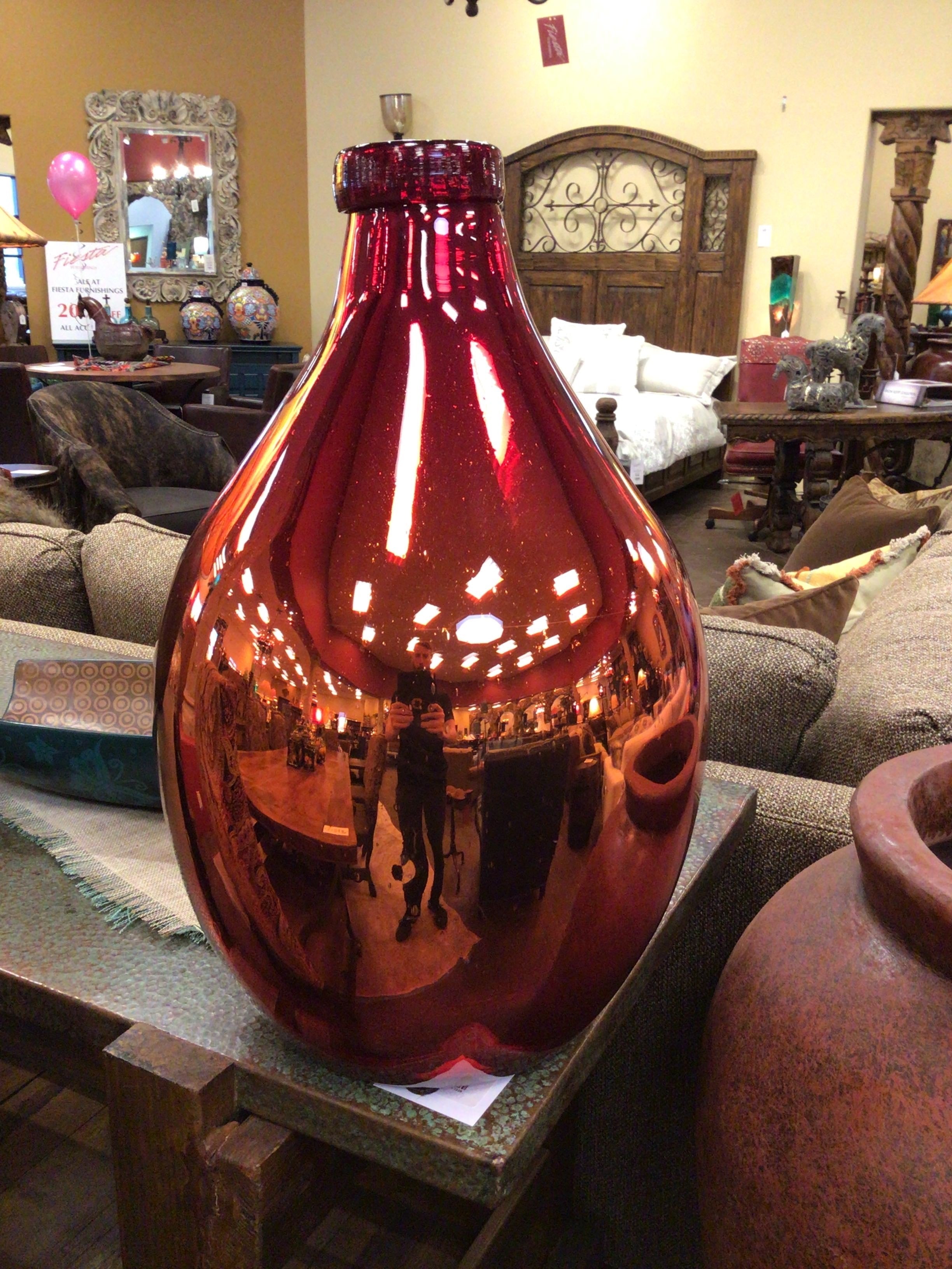 Large red glass vase on a table in a home setting with furniture and decor.