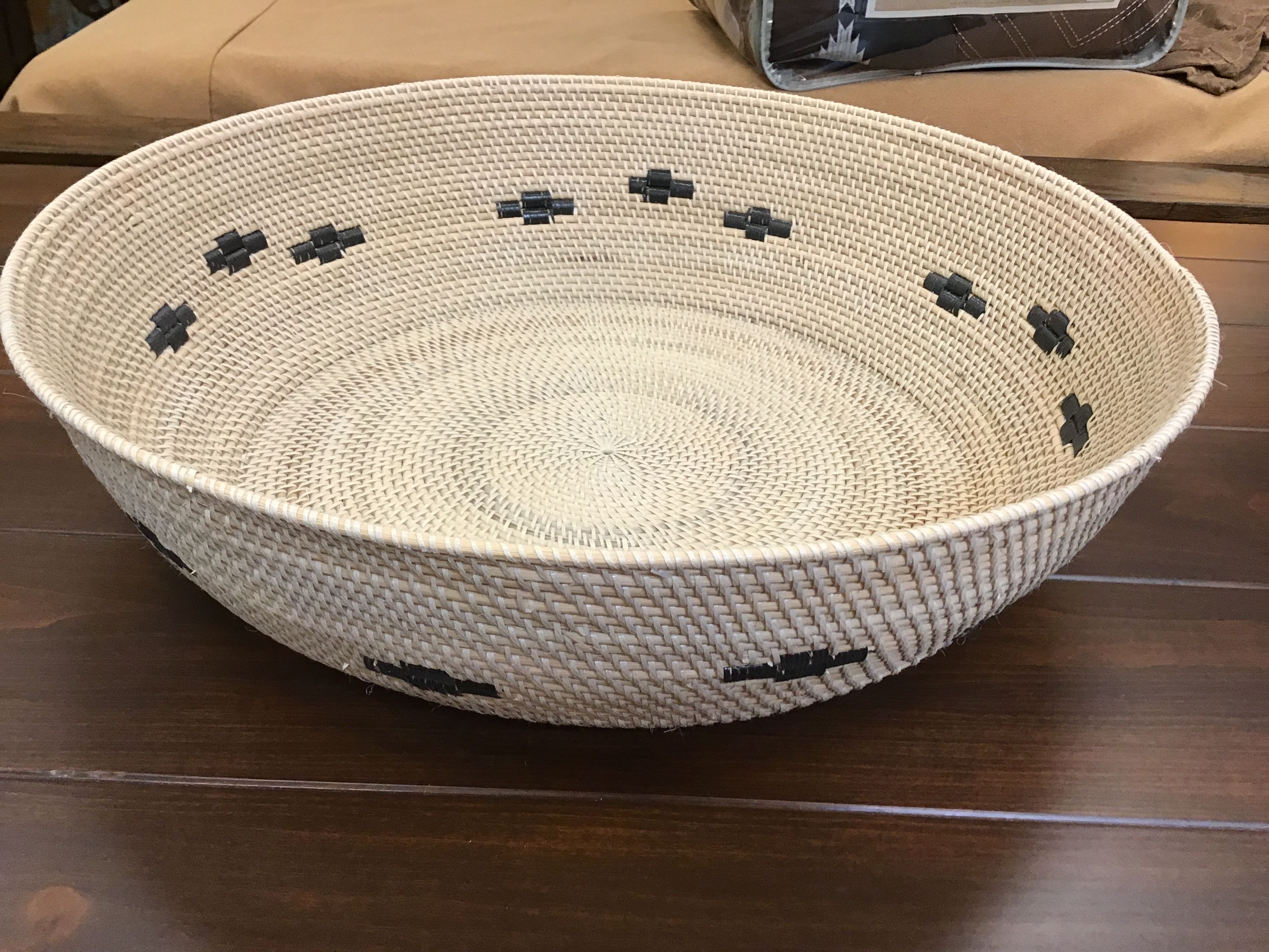 Woven basket with black decorative elements on a wooden surface