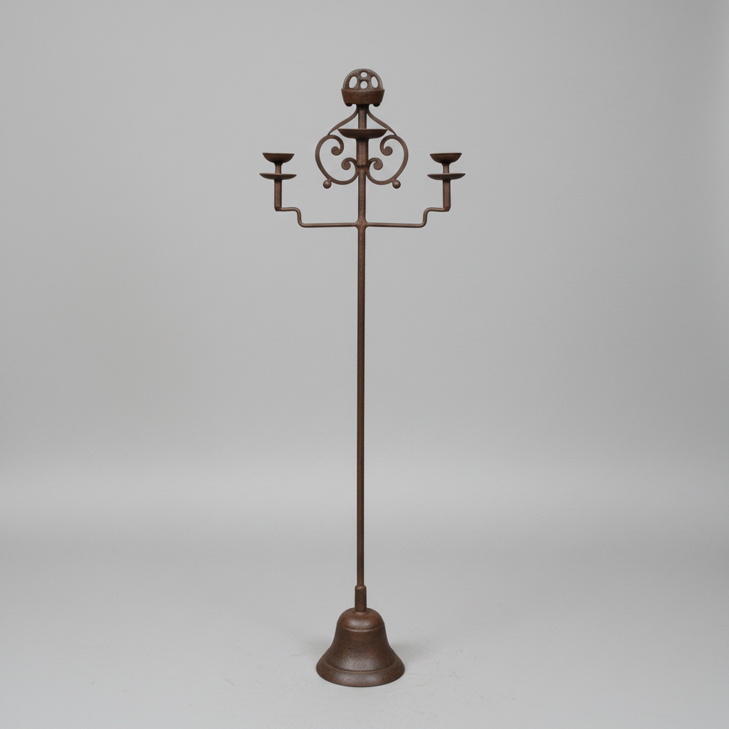 A dark brown metal three-arm candelabra with an ornate scrollwork top and a bell-shaped base, photographed against a neutral light gray studio background.