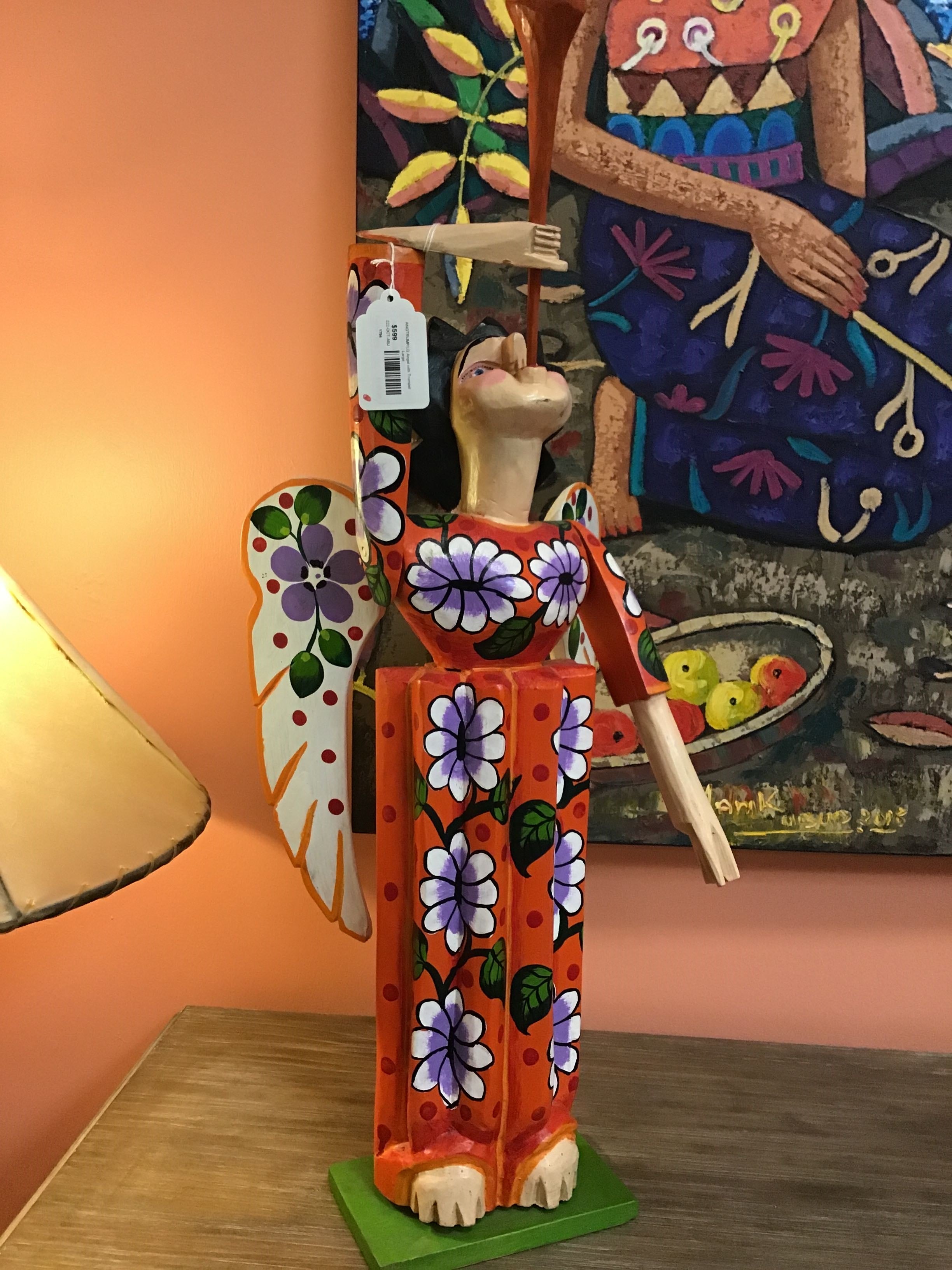 Colorful folk art figurine with floral patterns on a wooden surface.