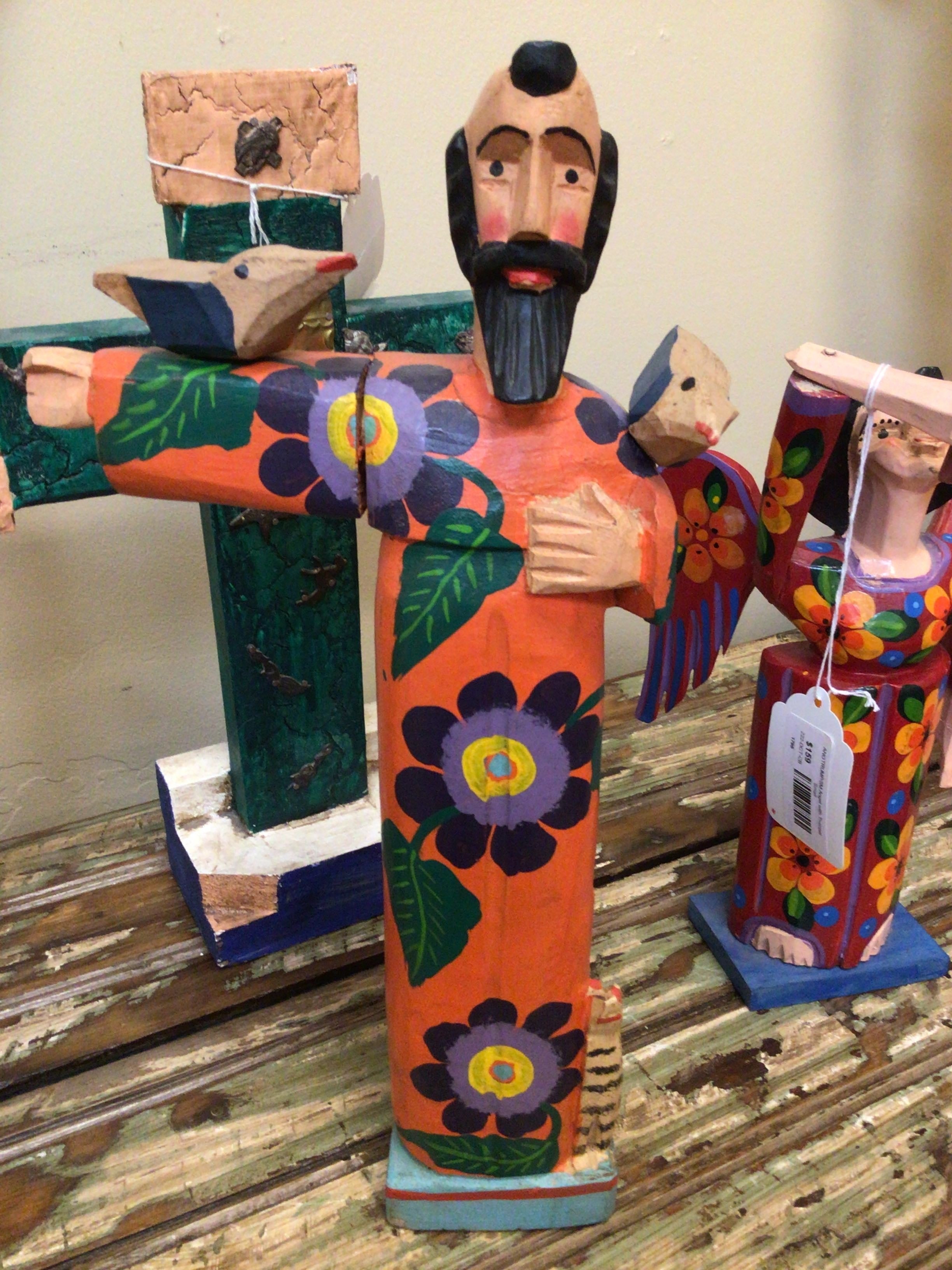Colorful wooden figurine with floral designs on a rustic surface