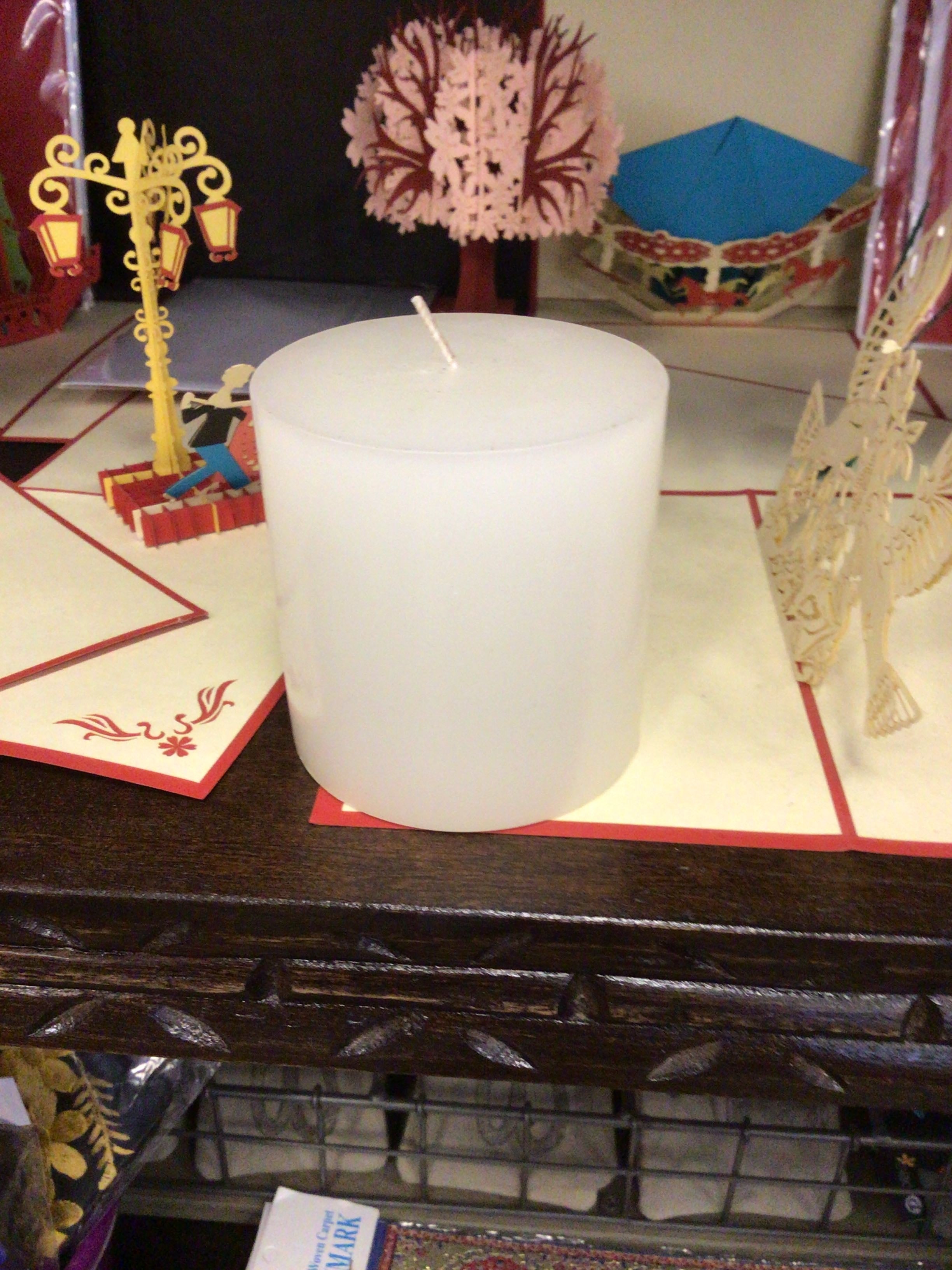 White candle on a decorative surface with festive items in the background