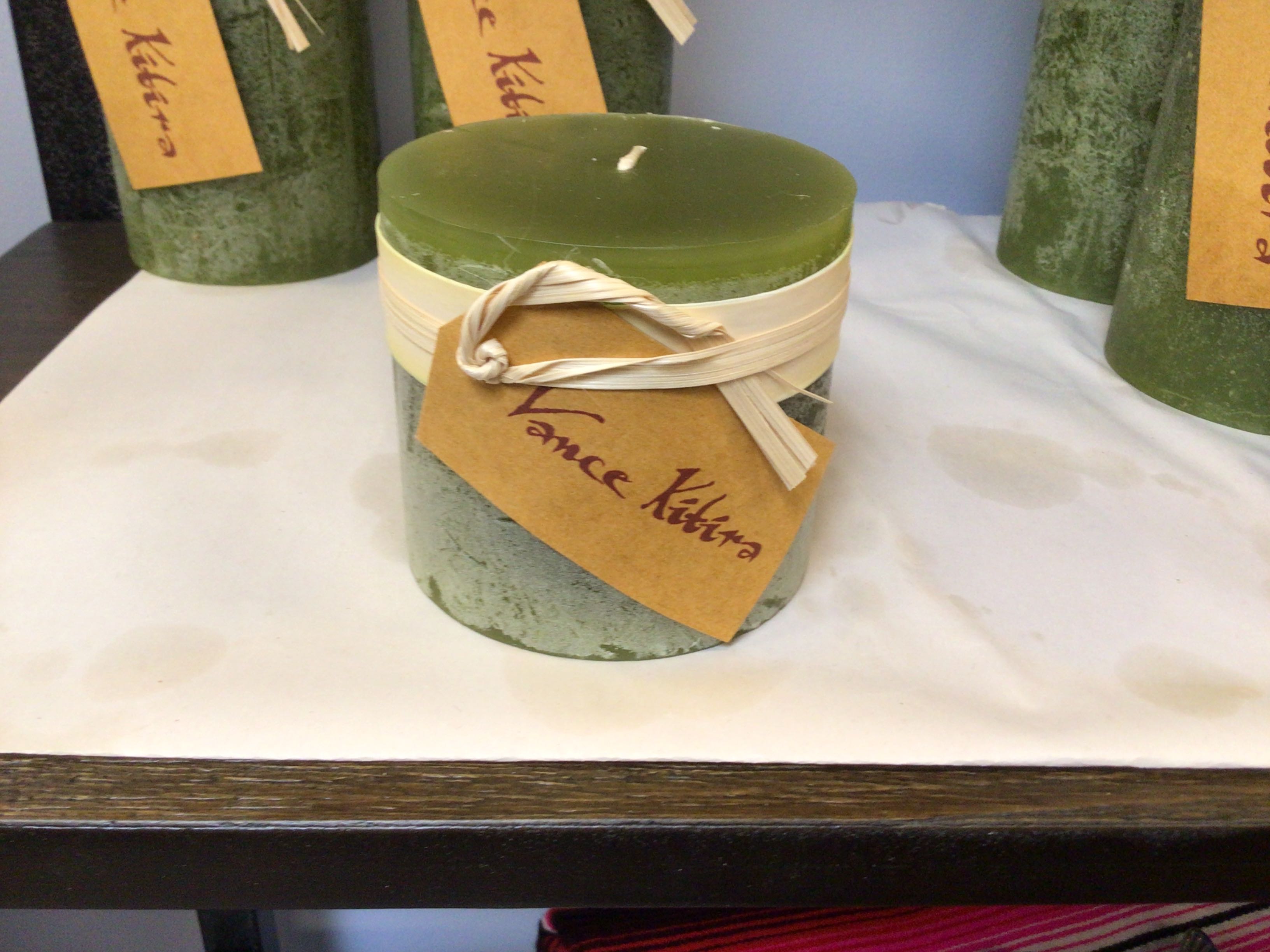 Green candle with a label on a white surface