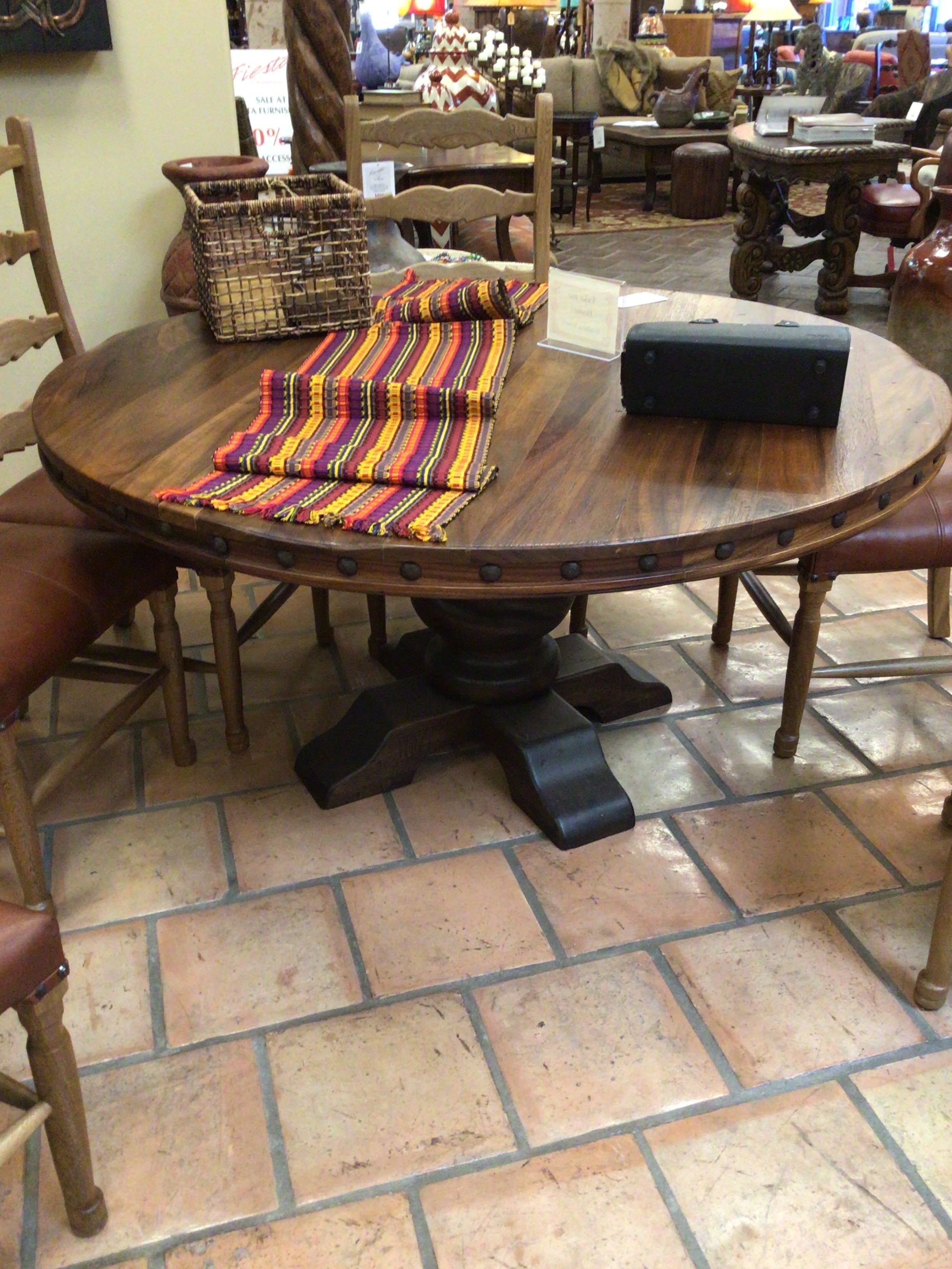 Round wooden table with a striped runner on a tiled floor in a store setting