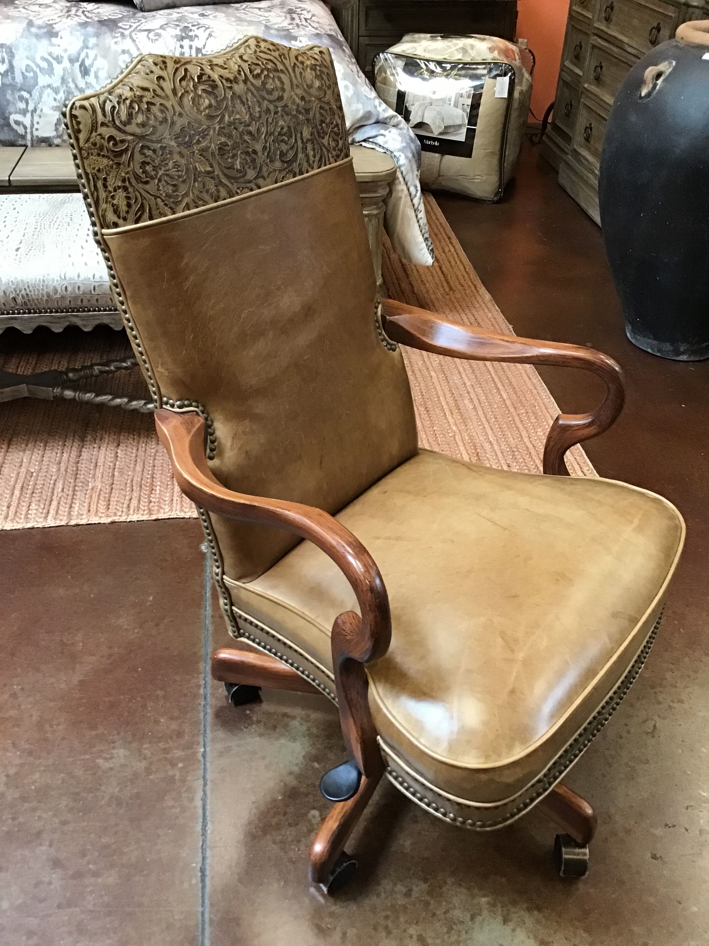 Brown leather office chair with wooden armrests in a room setting.