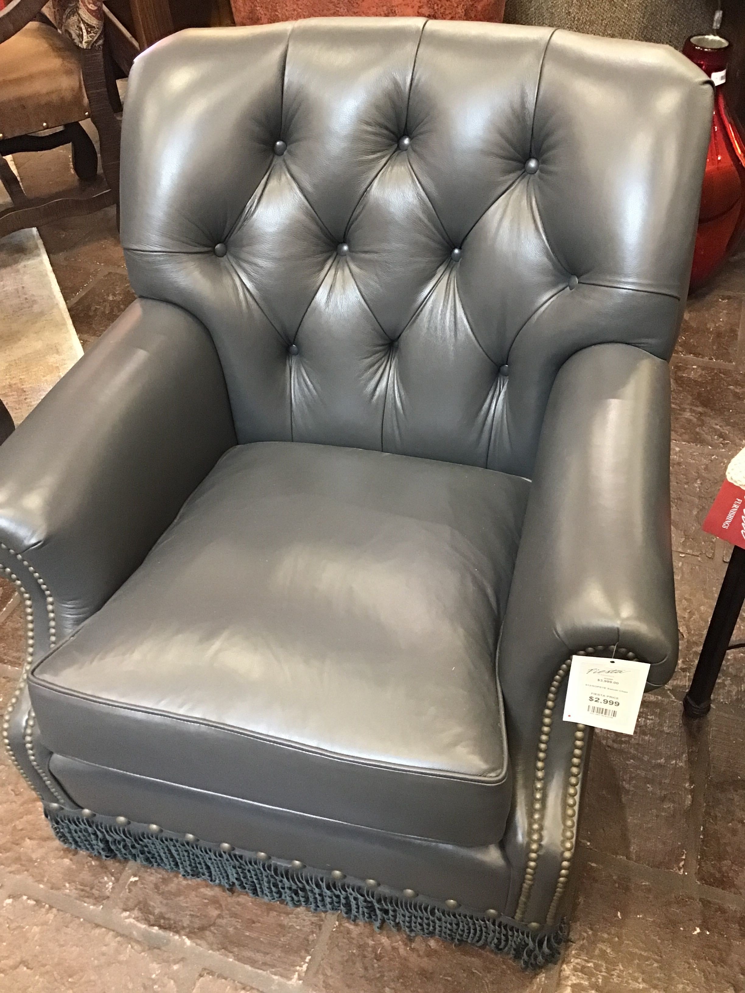 steel blue tufted armchair with decorative fringe on a brown carpet