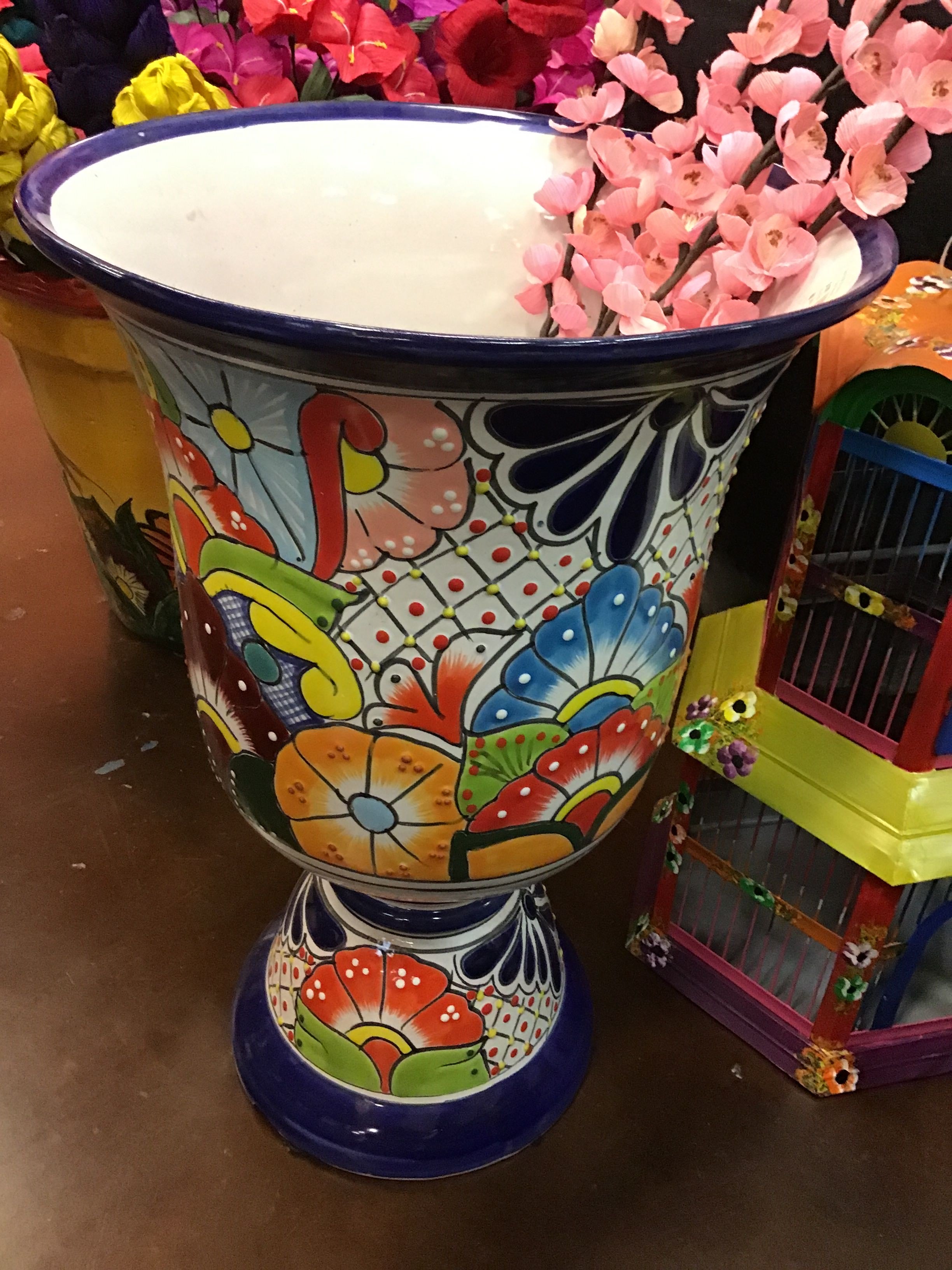 Colorful decorative vase with floral patterns on a table with flowers and toys in the background