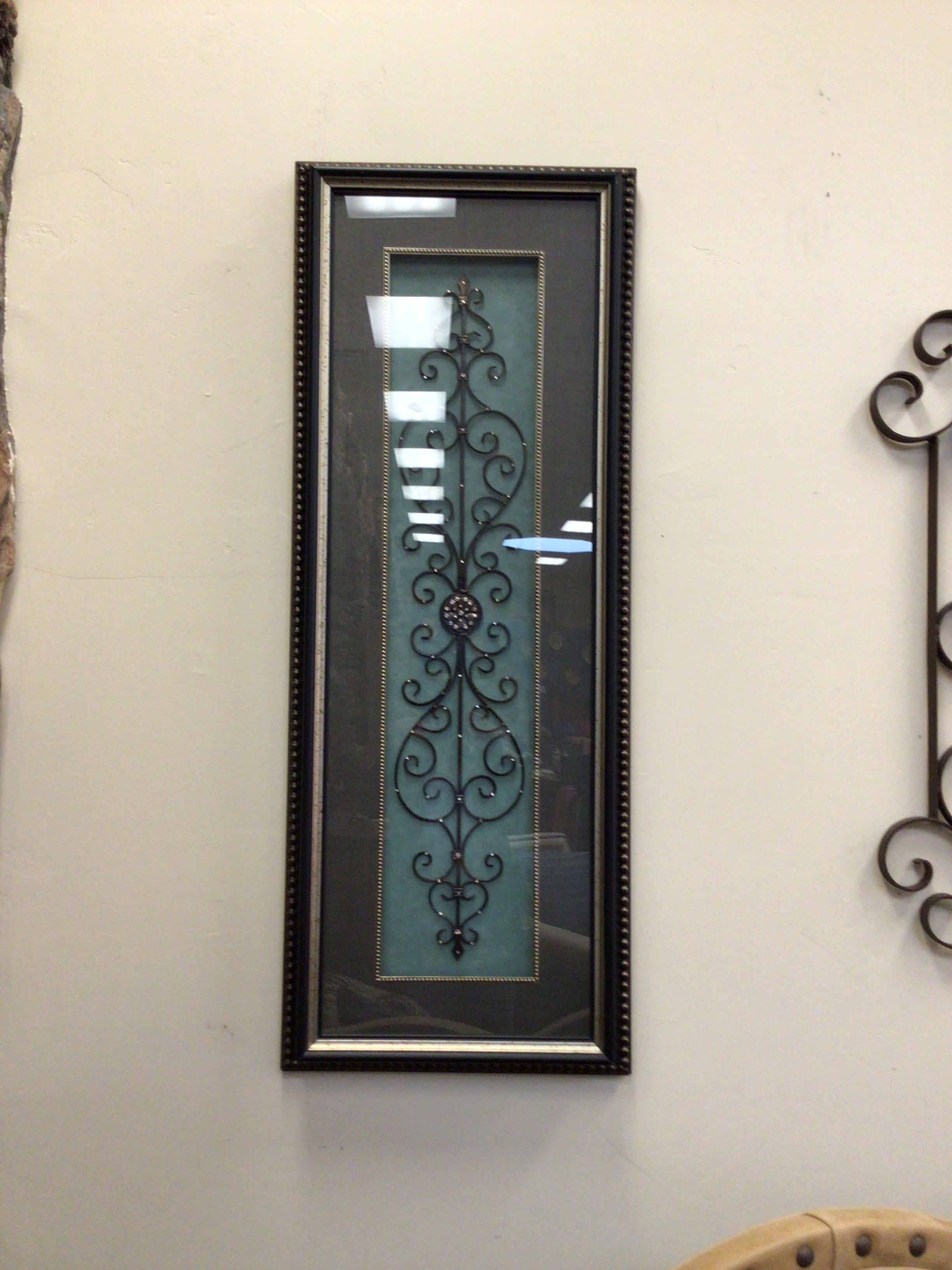 Decorative wall mirror with intricate black frame on a white wall