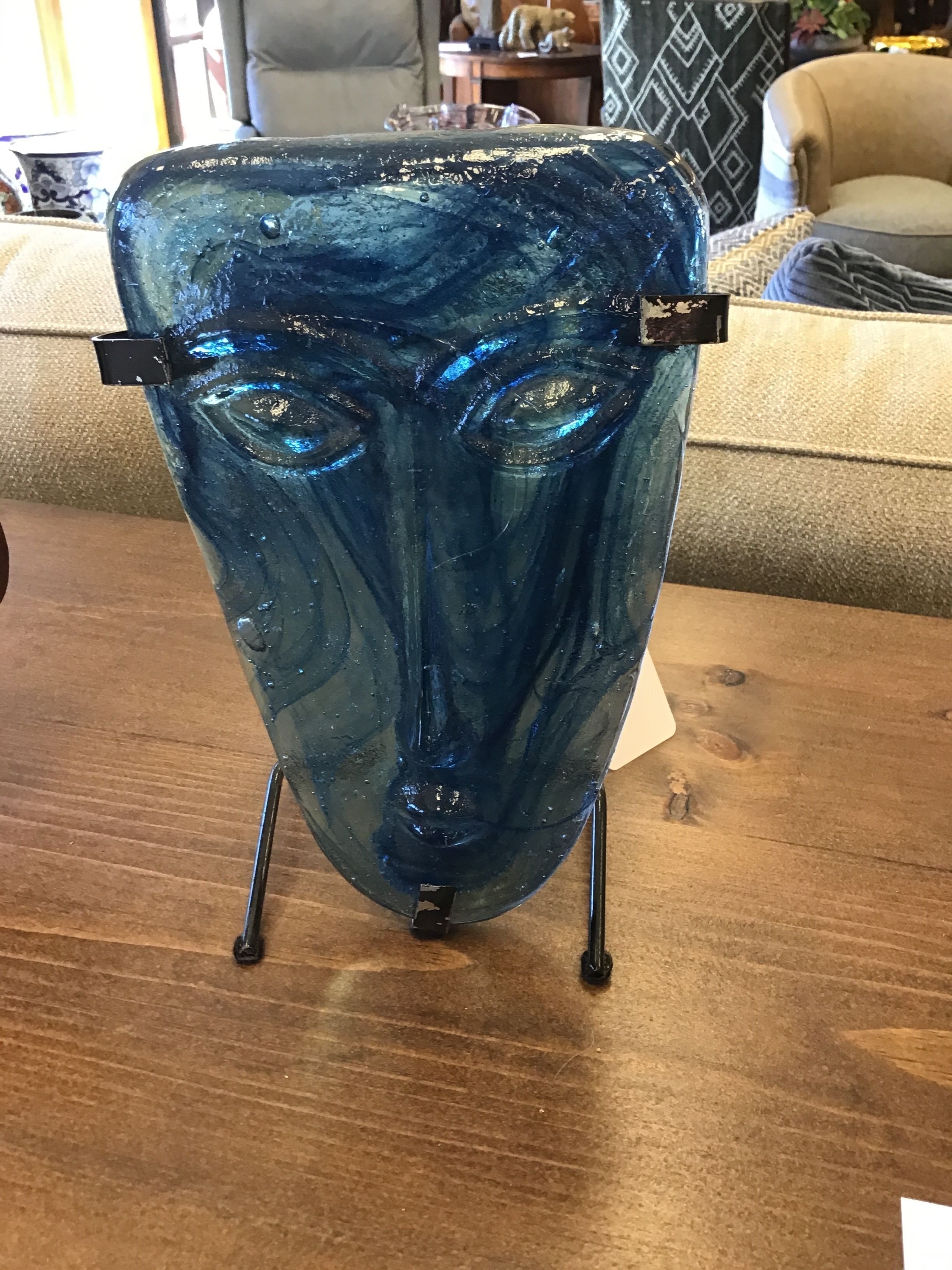 Blue glass face sculpture on a wooden table