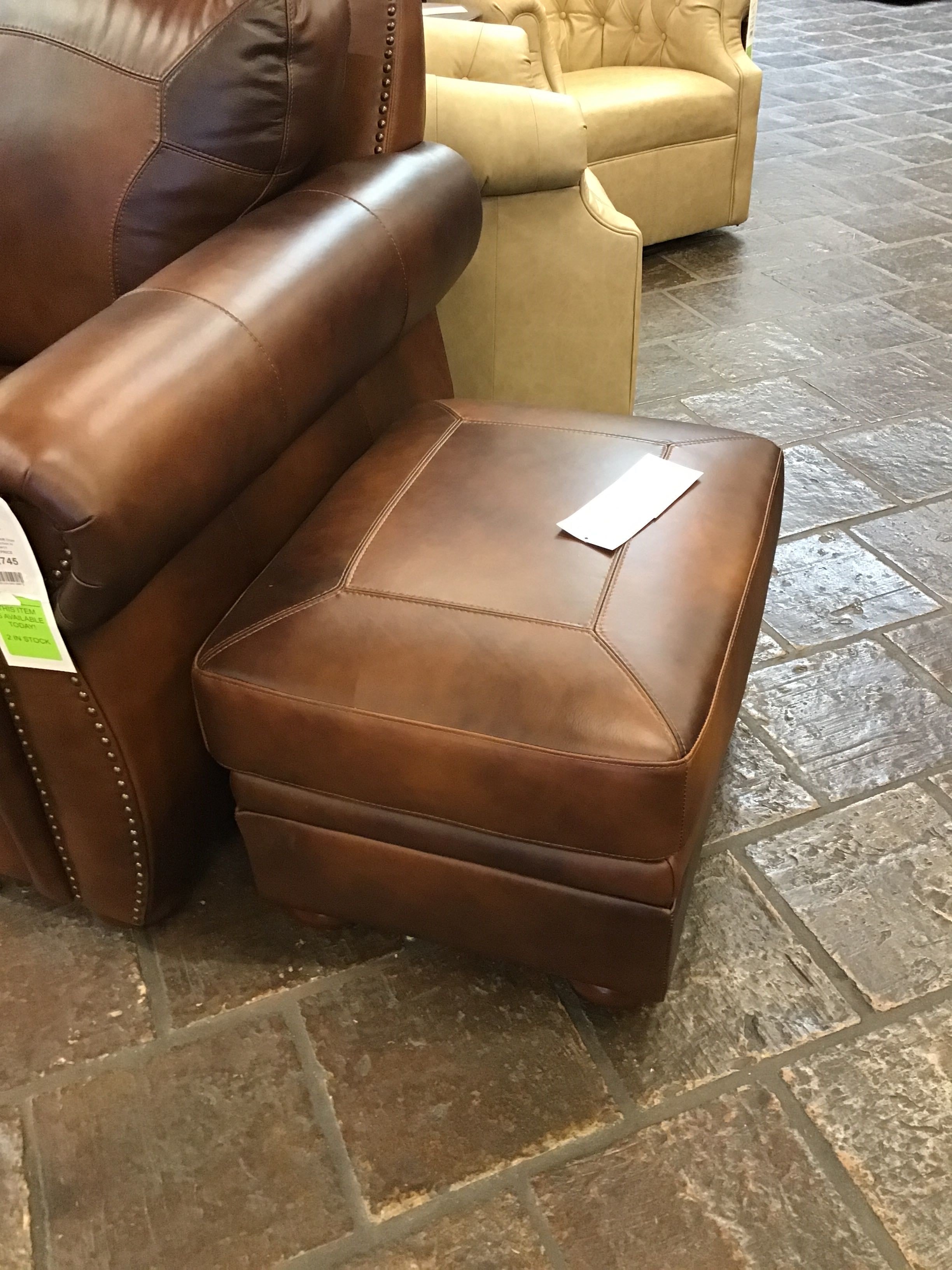 Brown leather recliner and ottoman on a stone floor