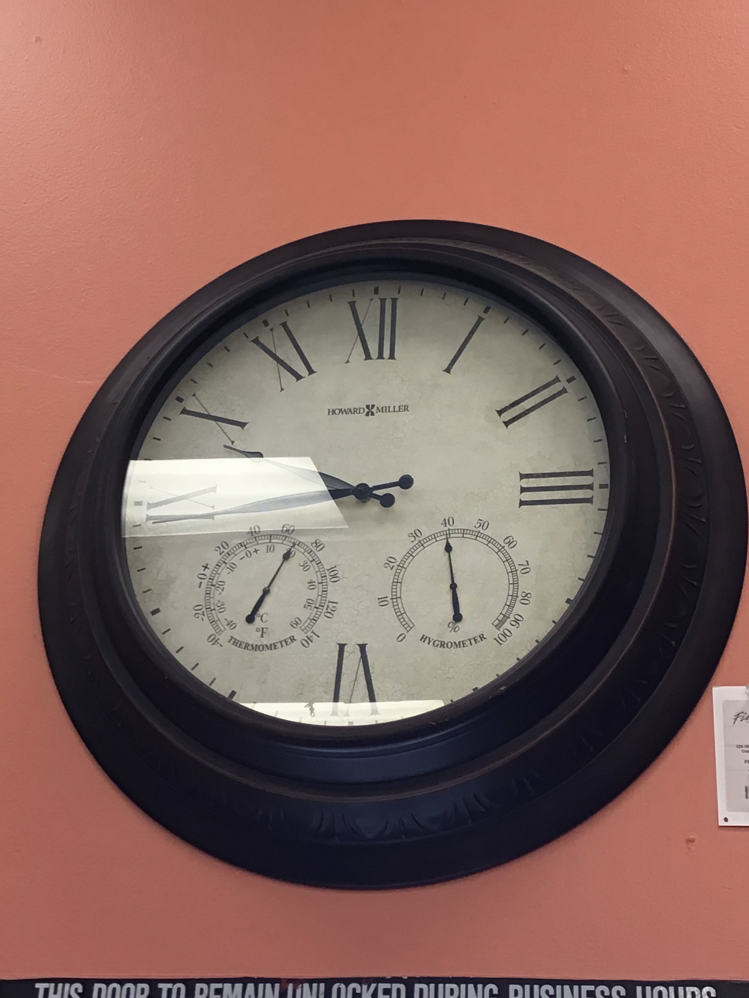 Large wall clock with Roman numerals on a red wall