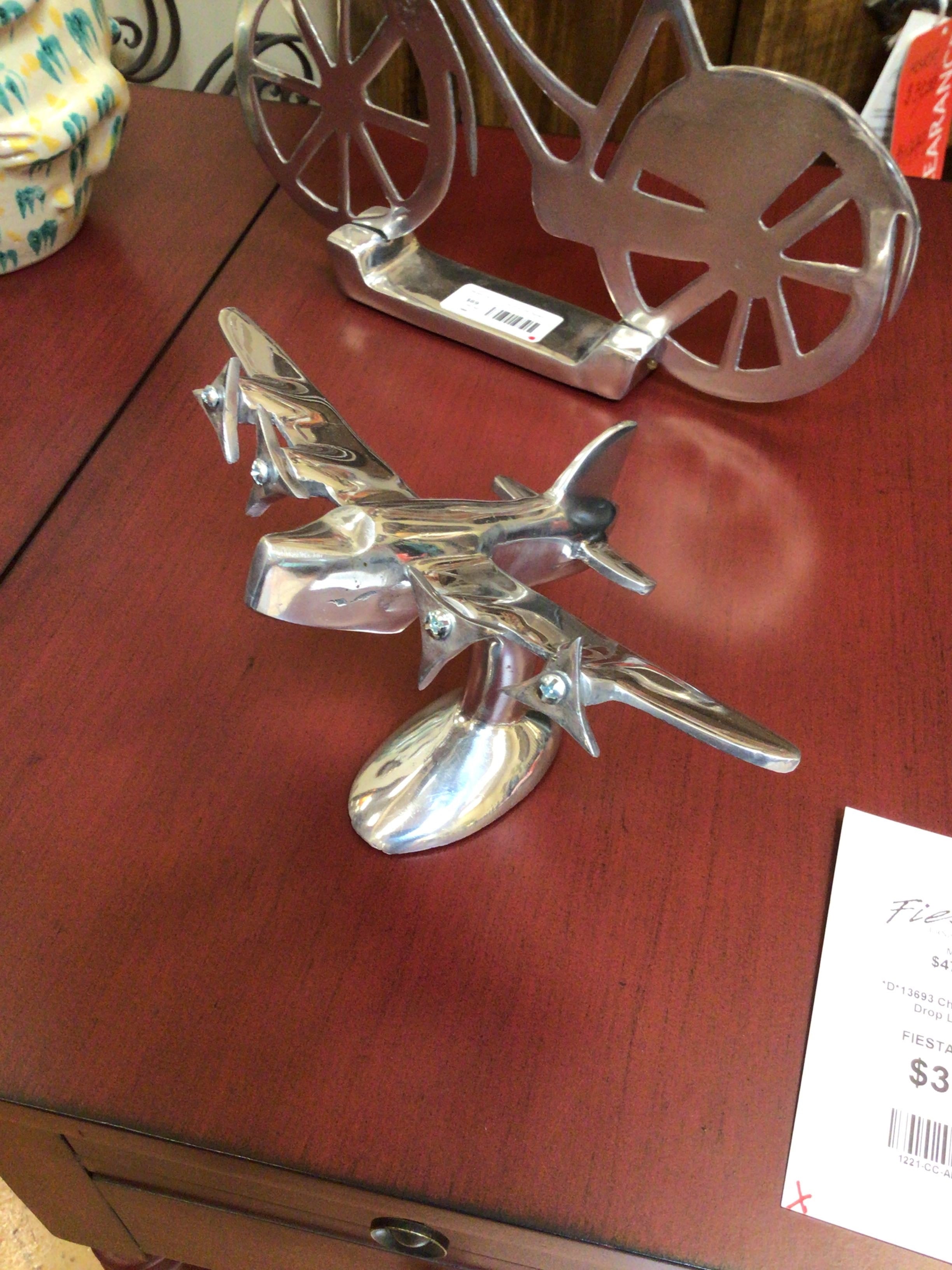 Metallic airplane ornament on a wooden surface with a price tag visible.