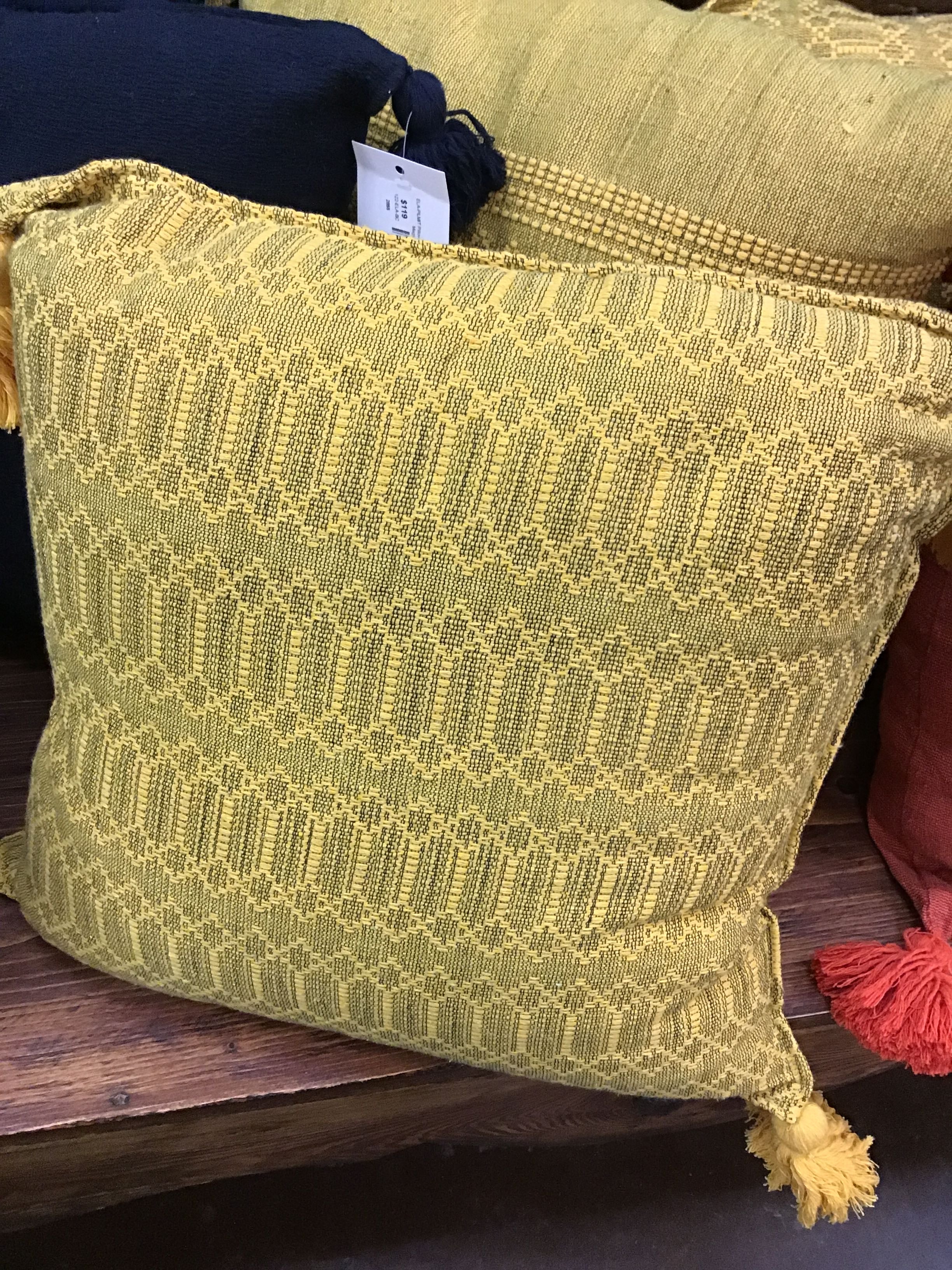 Green textured pillow with a tag on a wooden surface