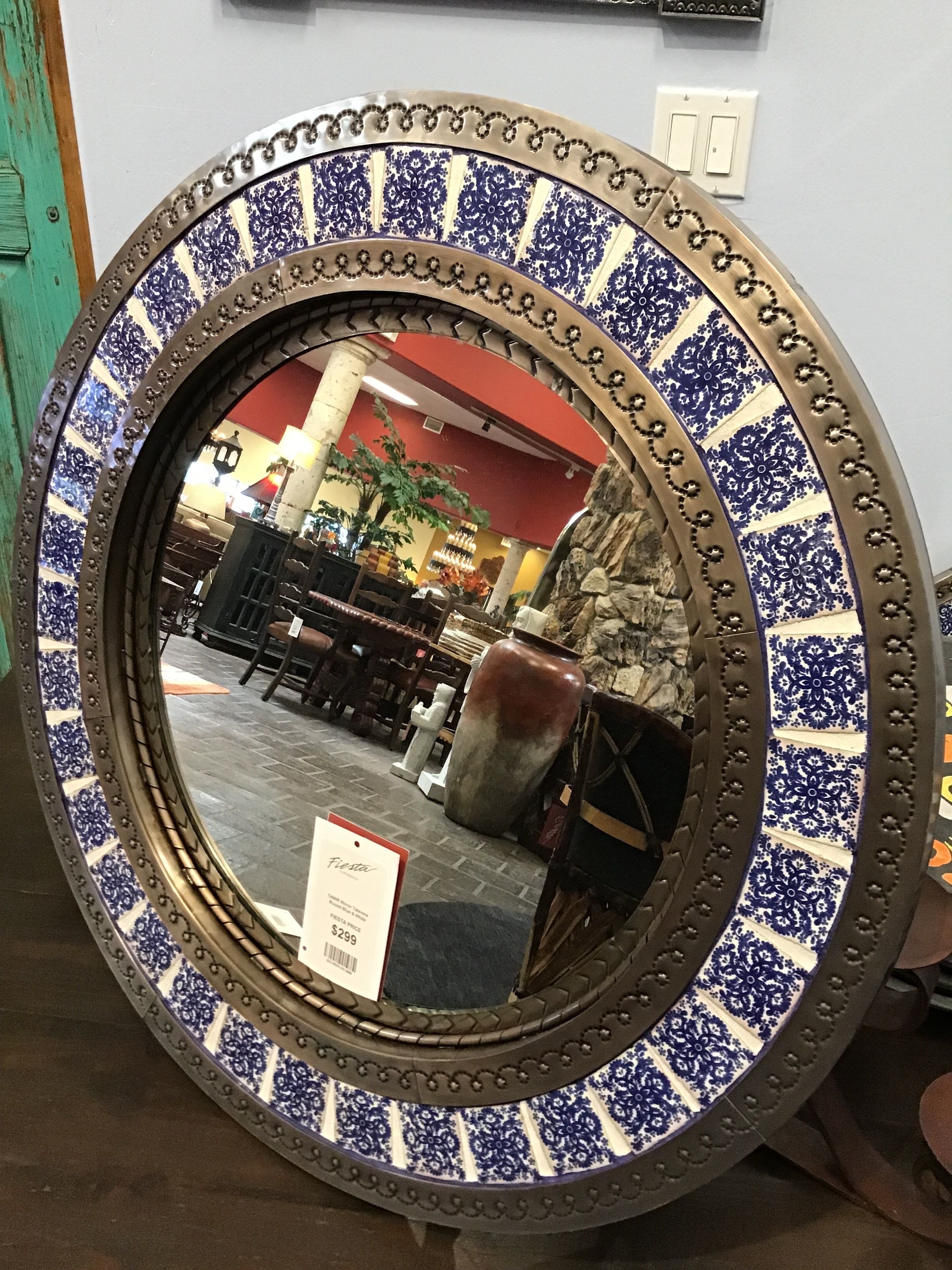 Round mirror with decorative blue and white frame on a wall