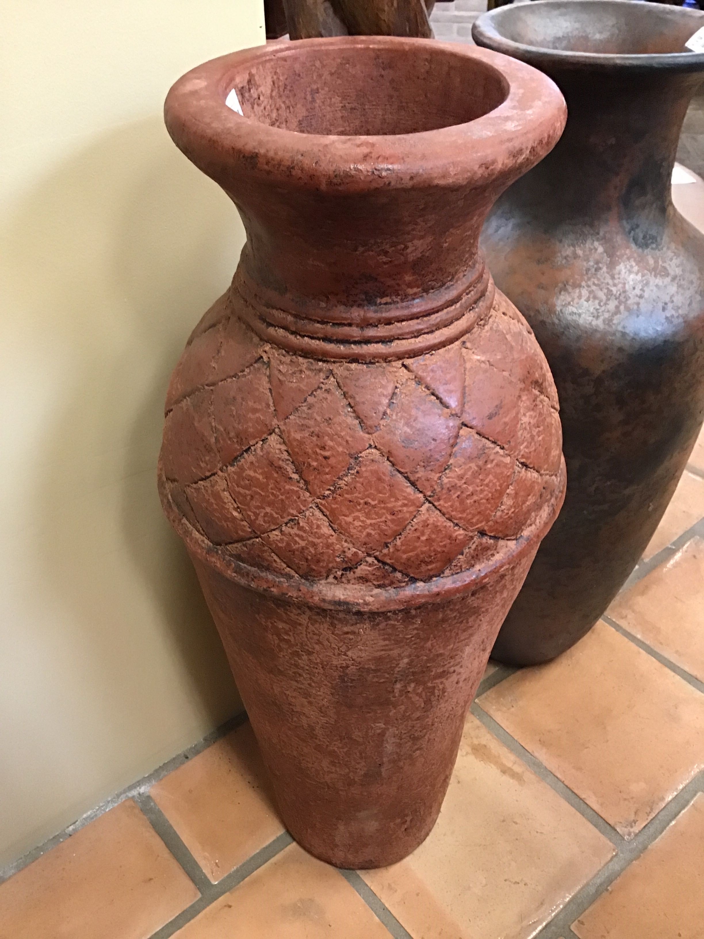 Terracotta pot with textured design on a tiled floor
