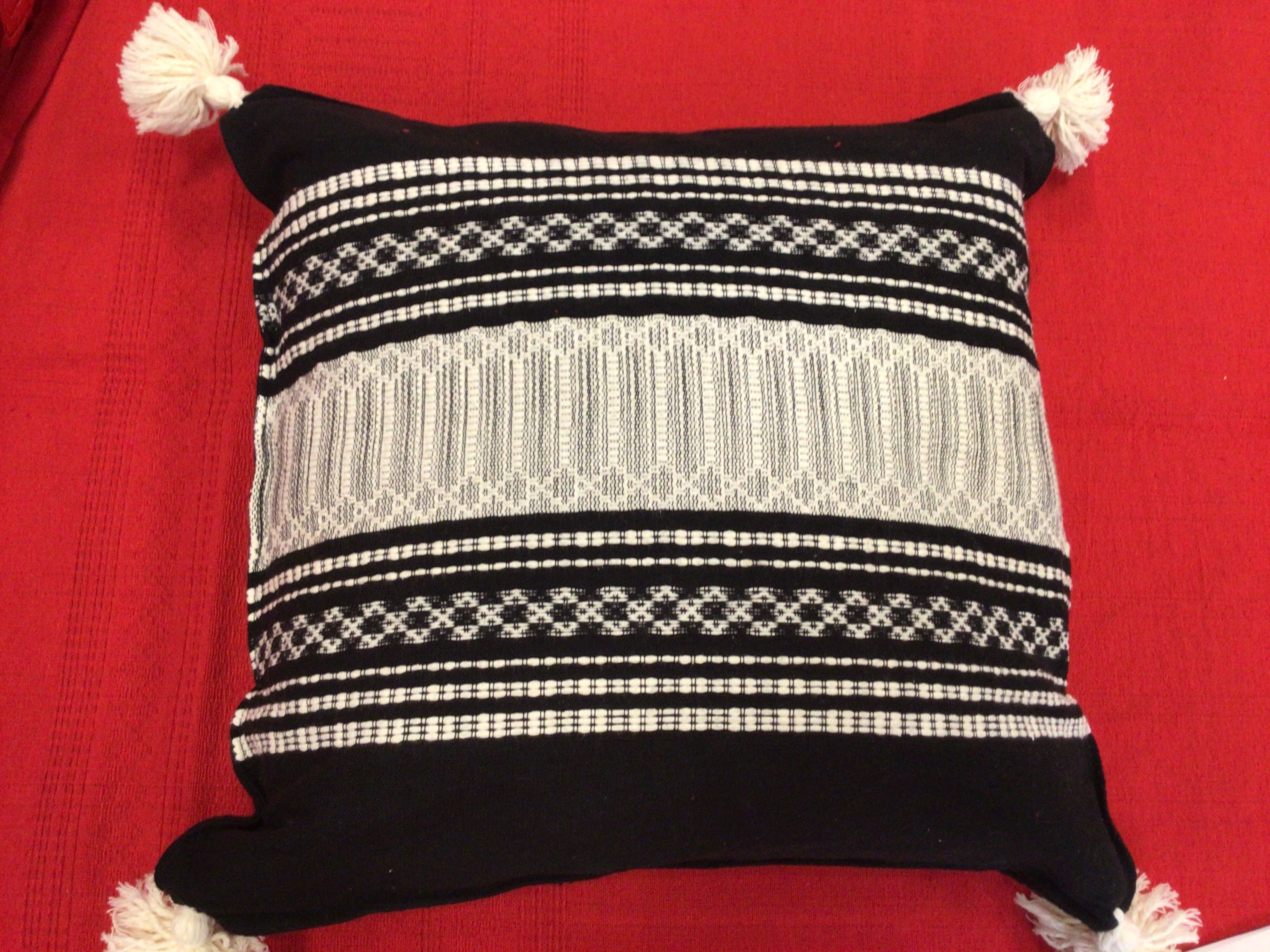 Decorative pillow with black and white pattern on a red background
