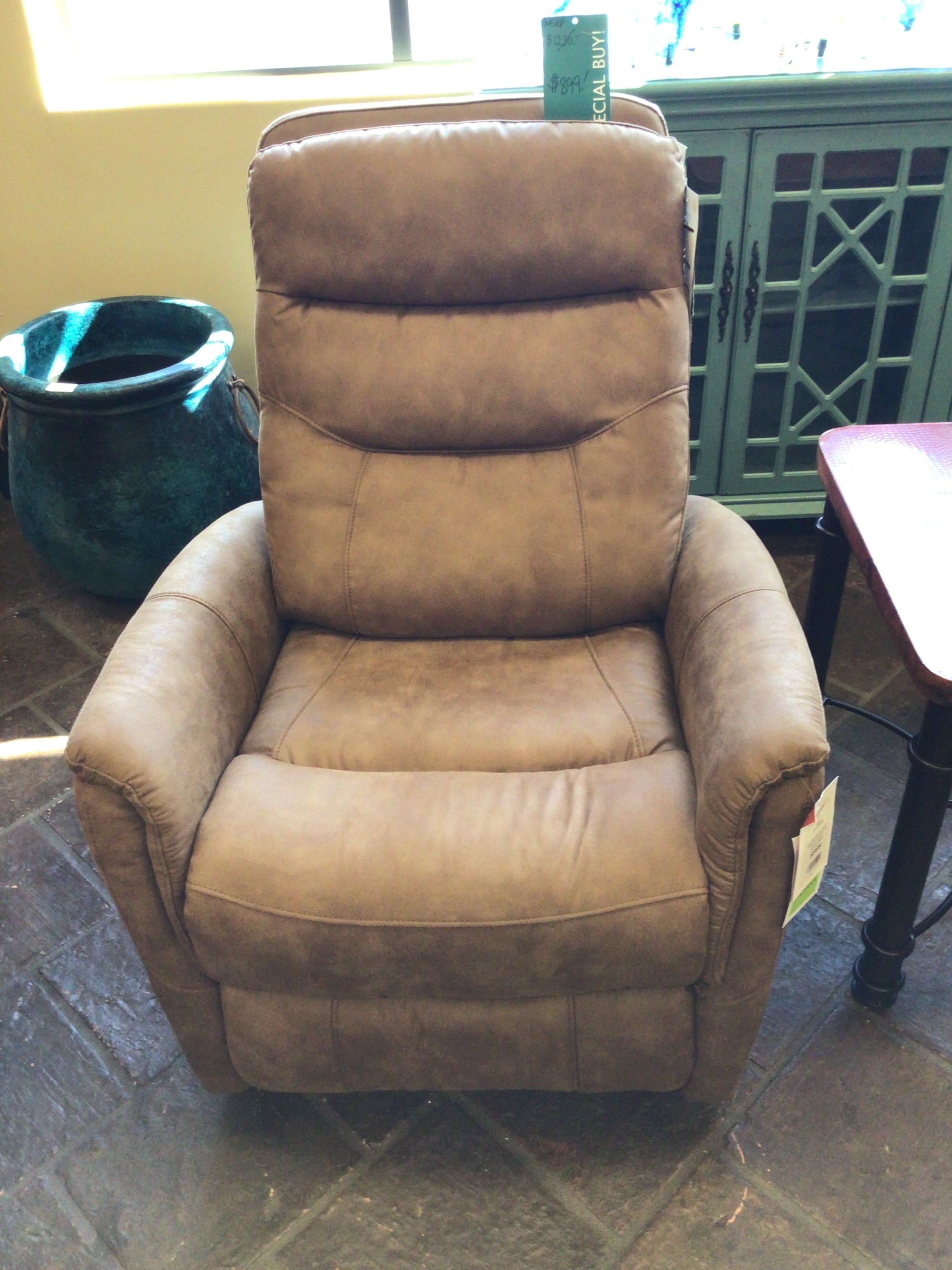 Brown leather recliner chair in a room with a green cabinet and a plant.
