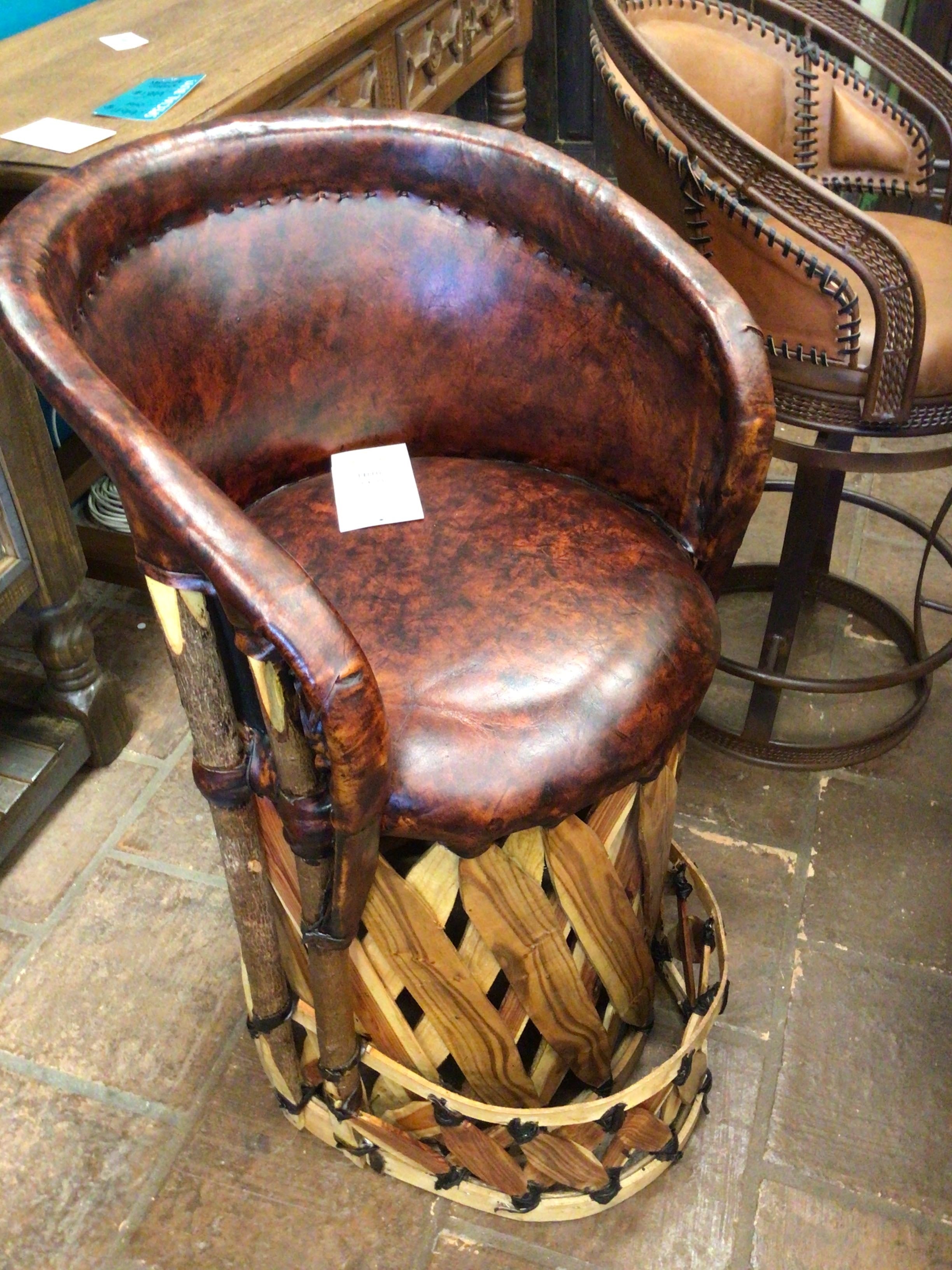 Brown leather bar stool with wooden base on a stone floor