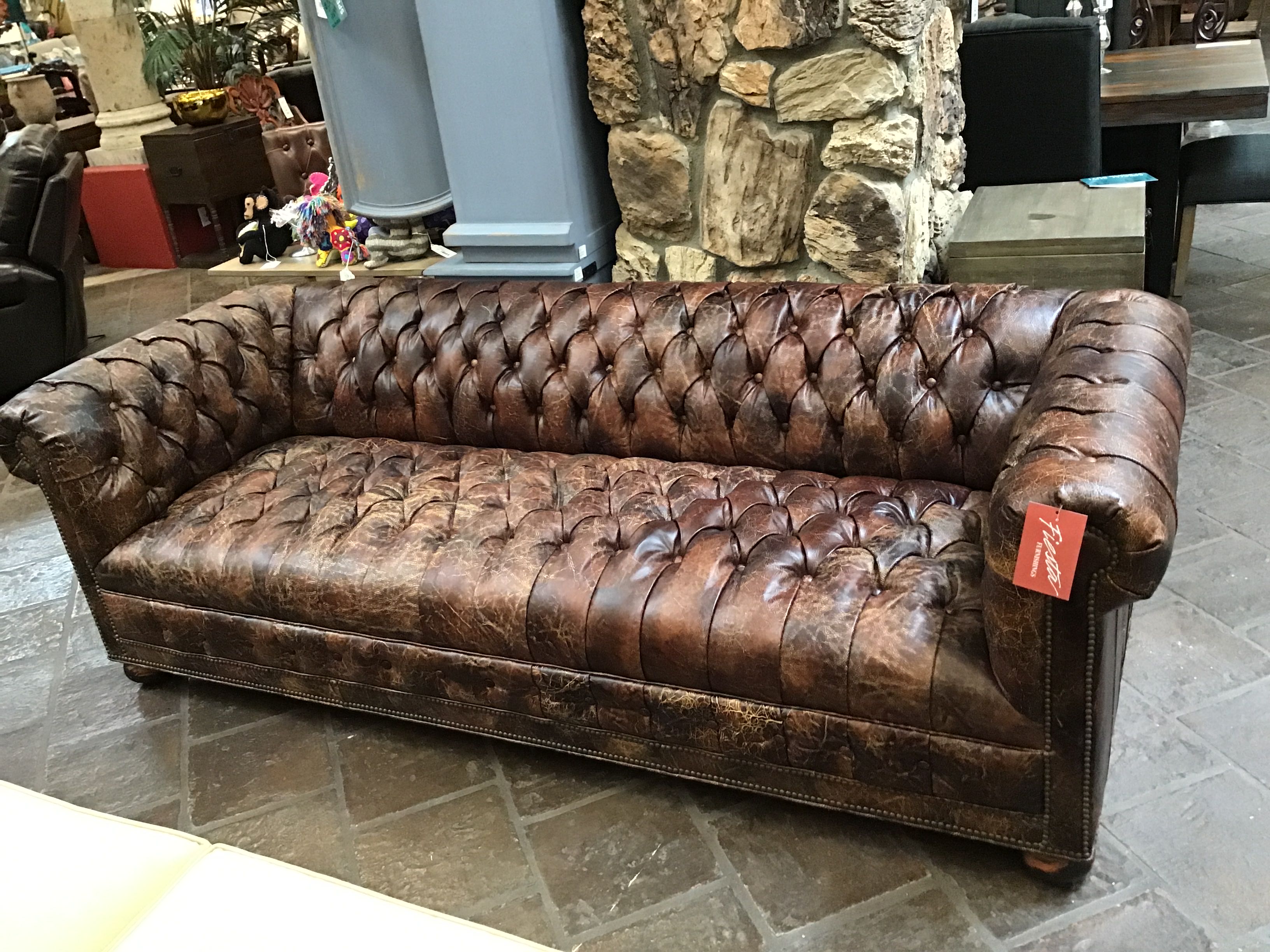 Brown leather sofa with a price tag in a store setting