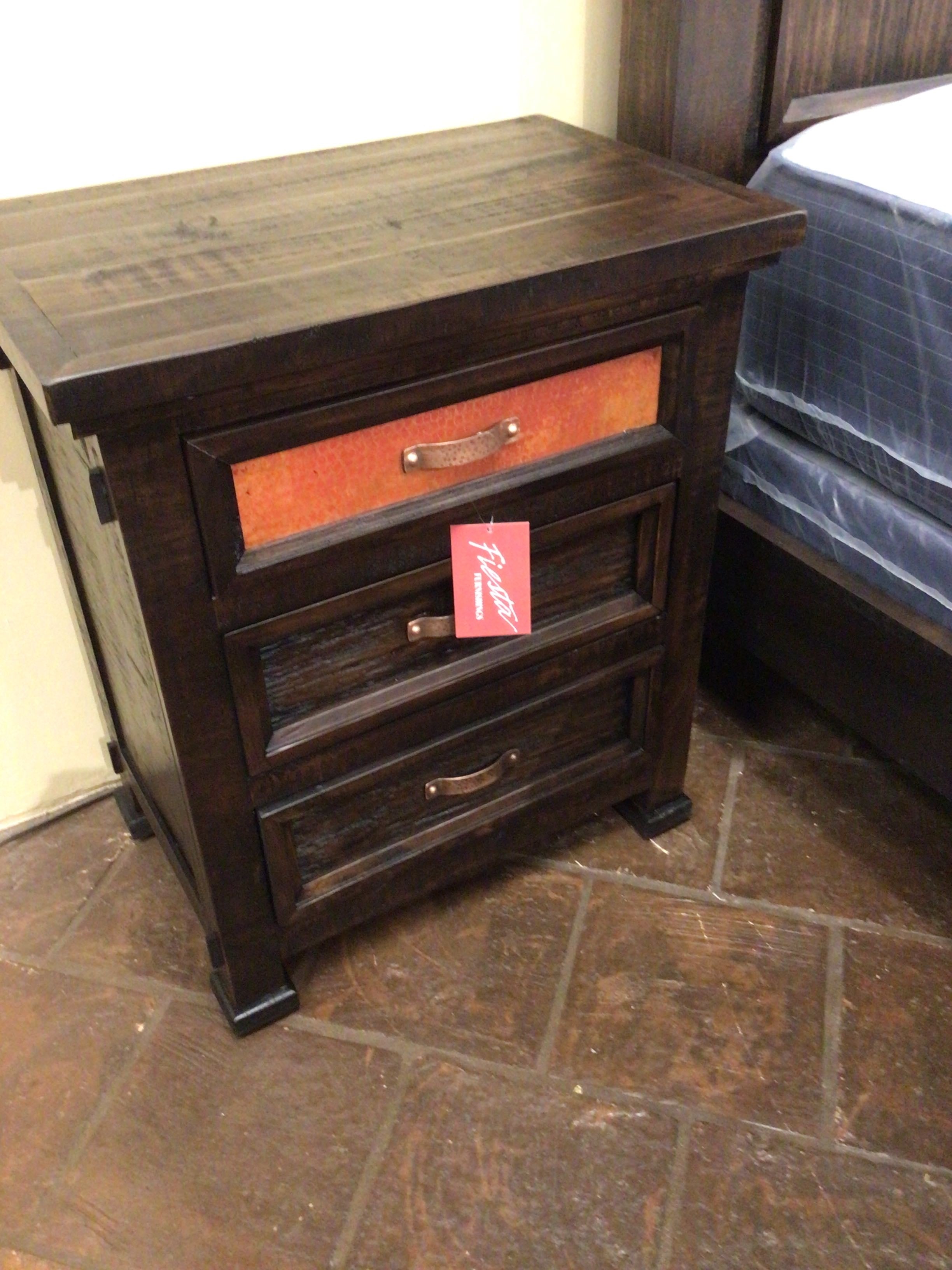 Wooden nightstand with orange drawer pull and price tag on a tiled floor.