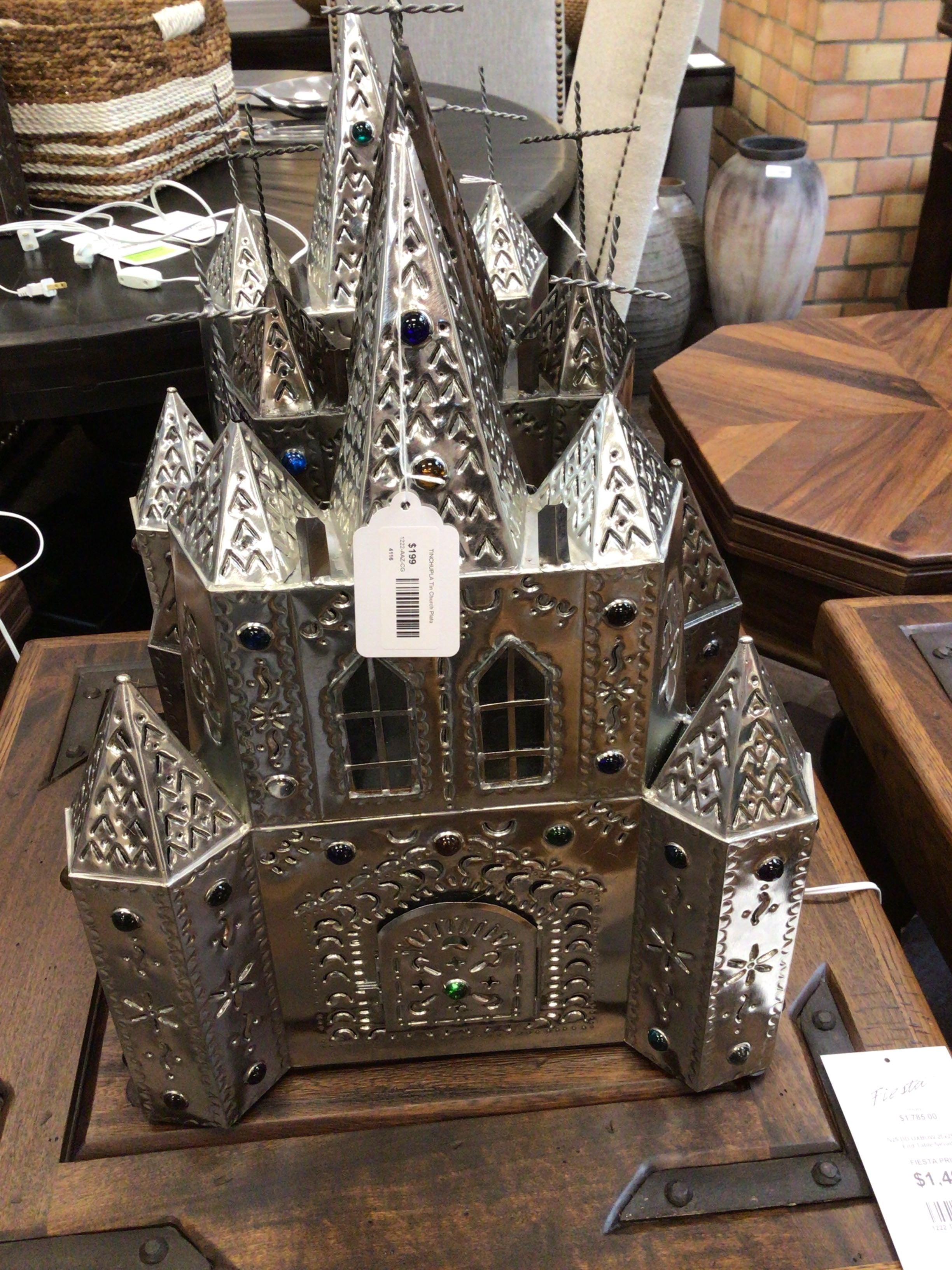 Decorative metal castle on a wooden surface with a tag attached