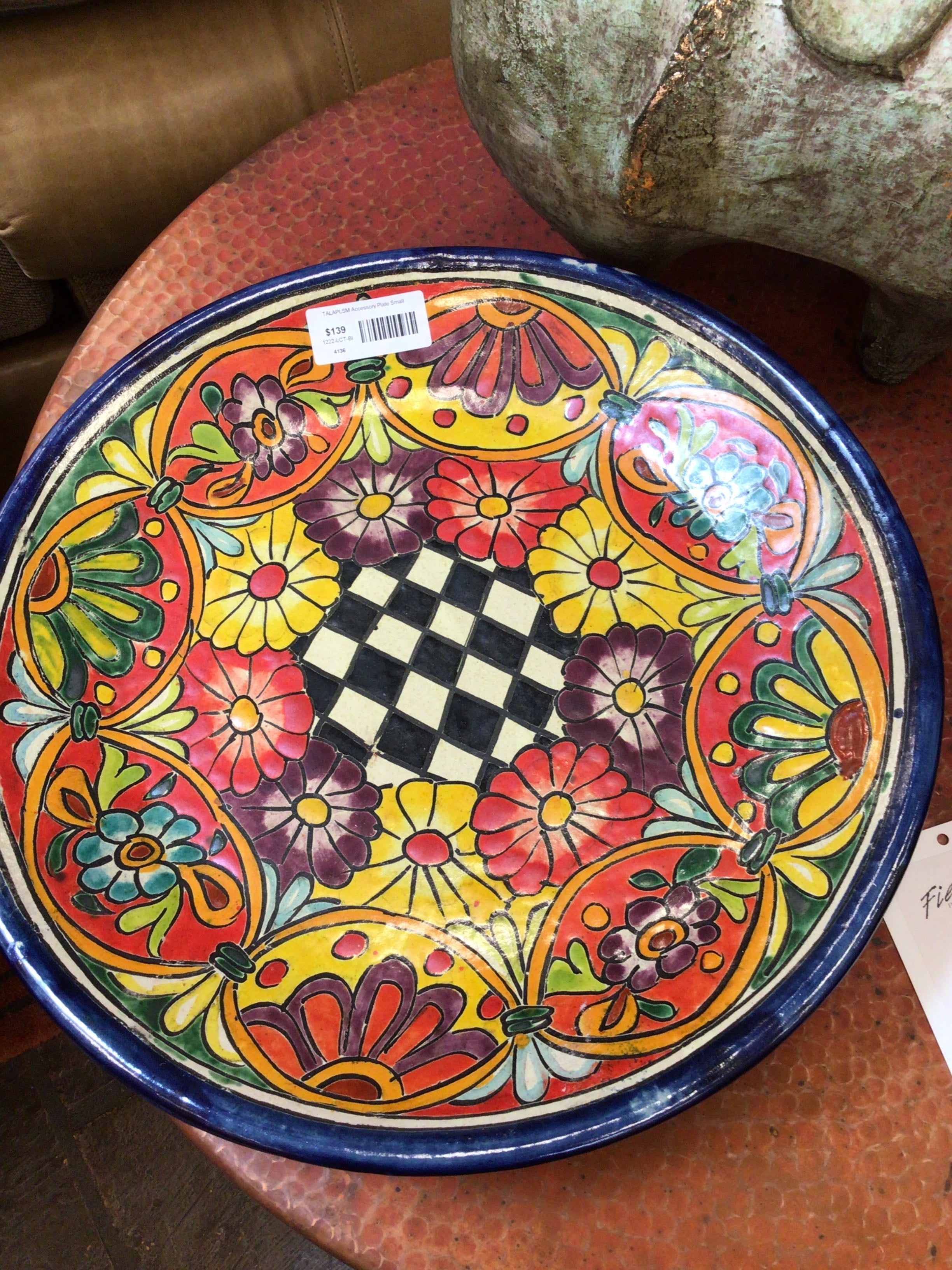 Decorative plate with colorful floral and geometric patterns on a wooden surface.