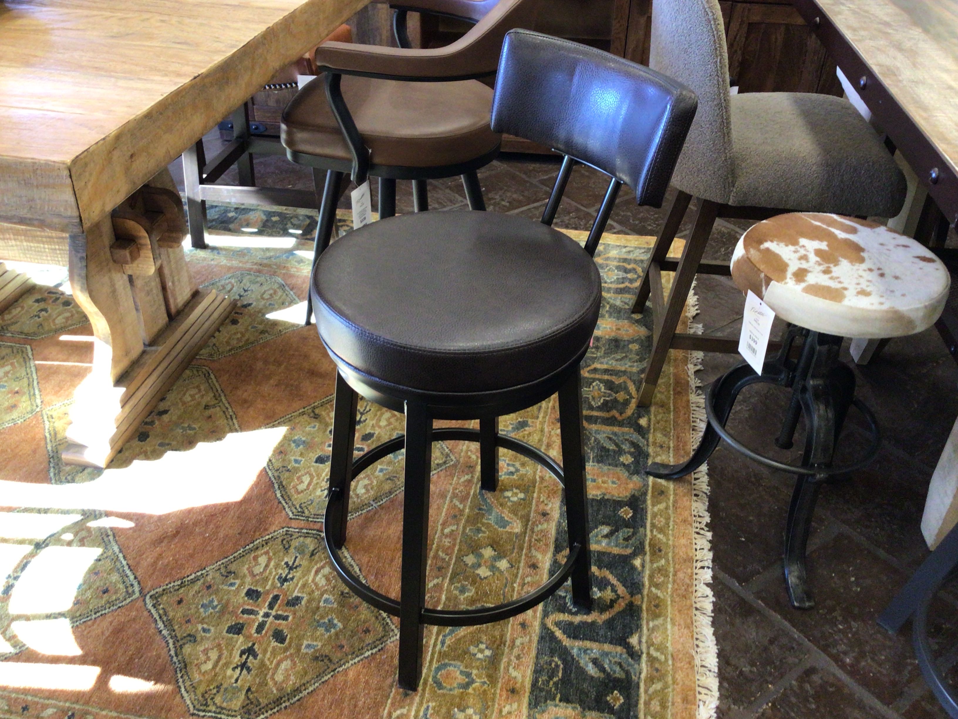 Bar stools in a rustic setting with wooden tables and a patterned rug.
