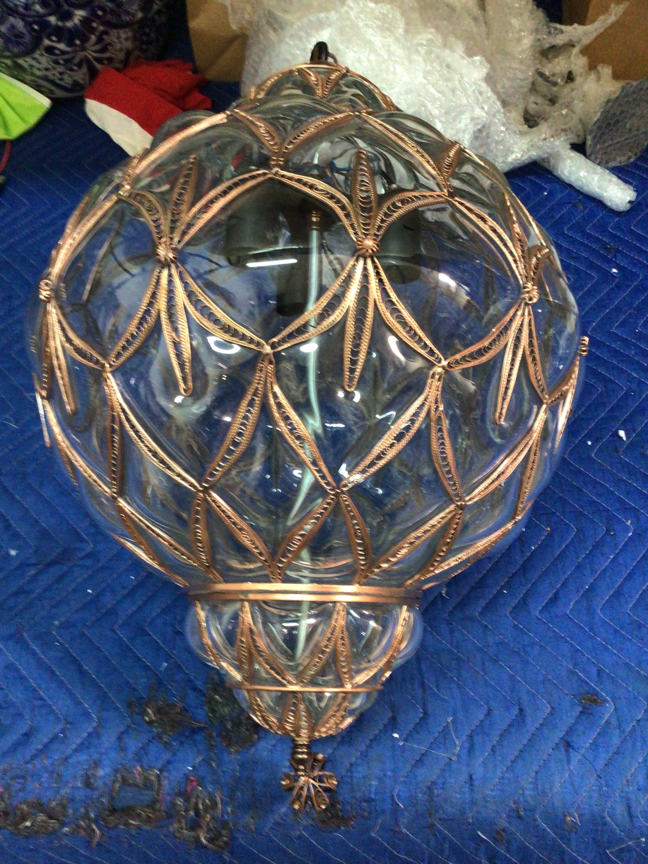 Decorative glass sphere with bronze wirework on a blue textured surface