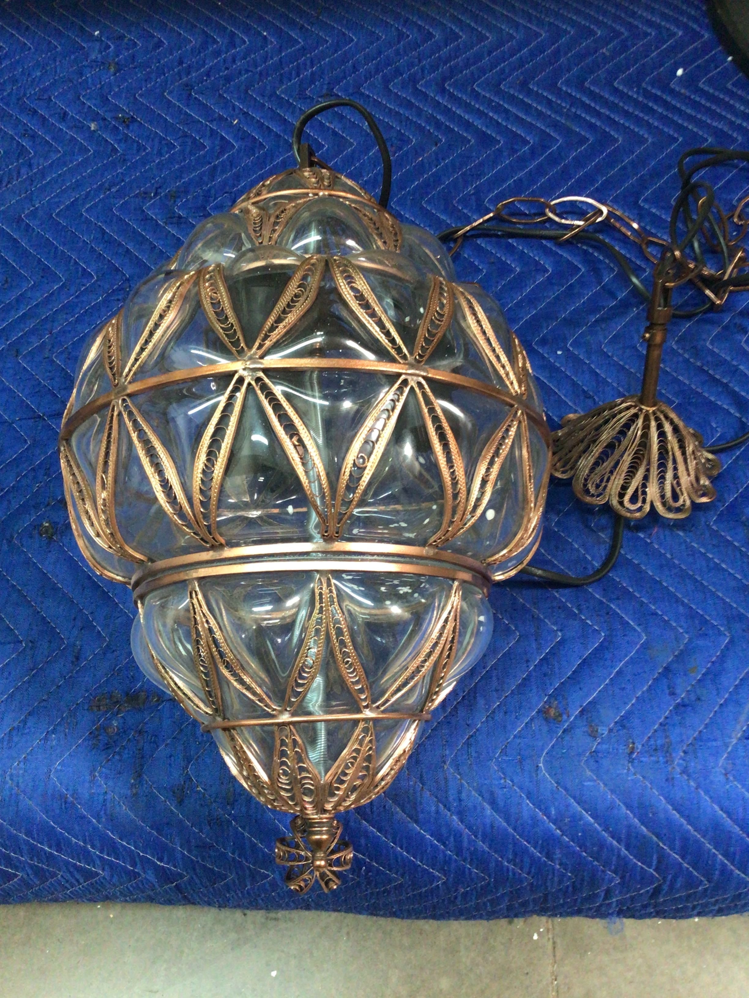 Decorative glass light fixture with gold metalwork on a blue textured surface