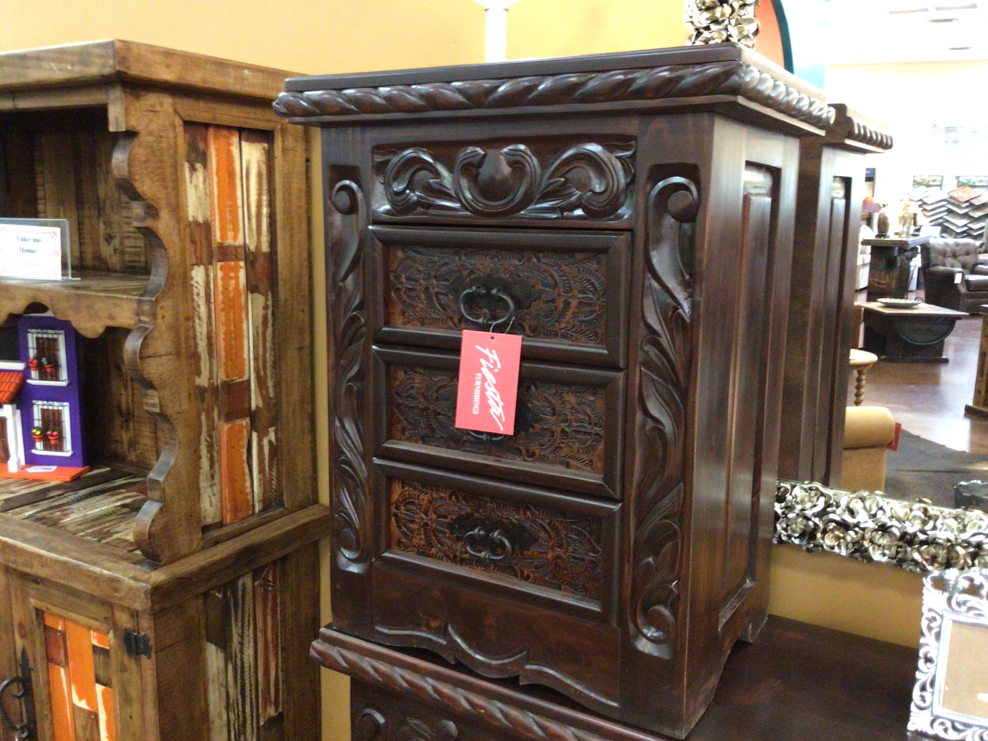 Carved wooden nightstand with decorative elements in a store setting